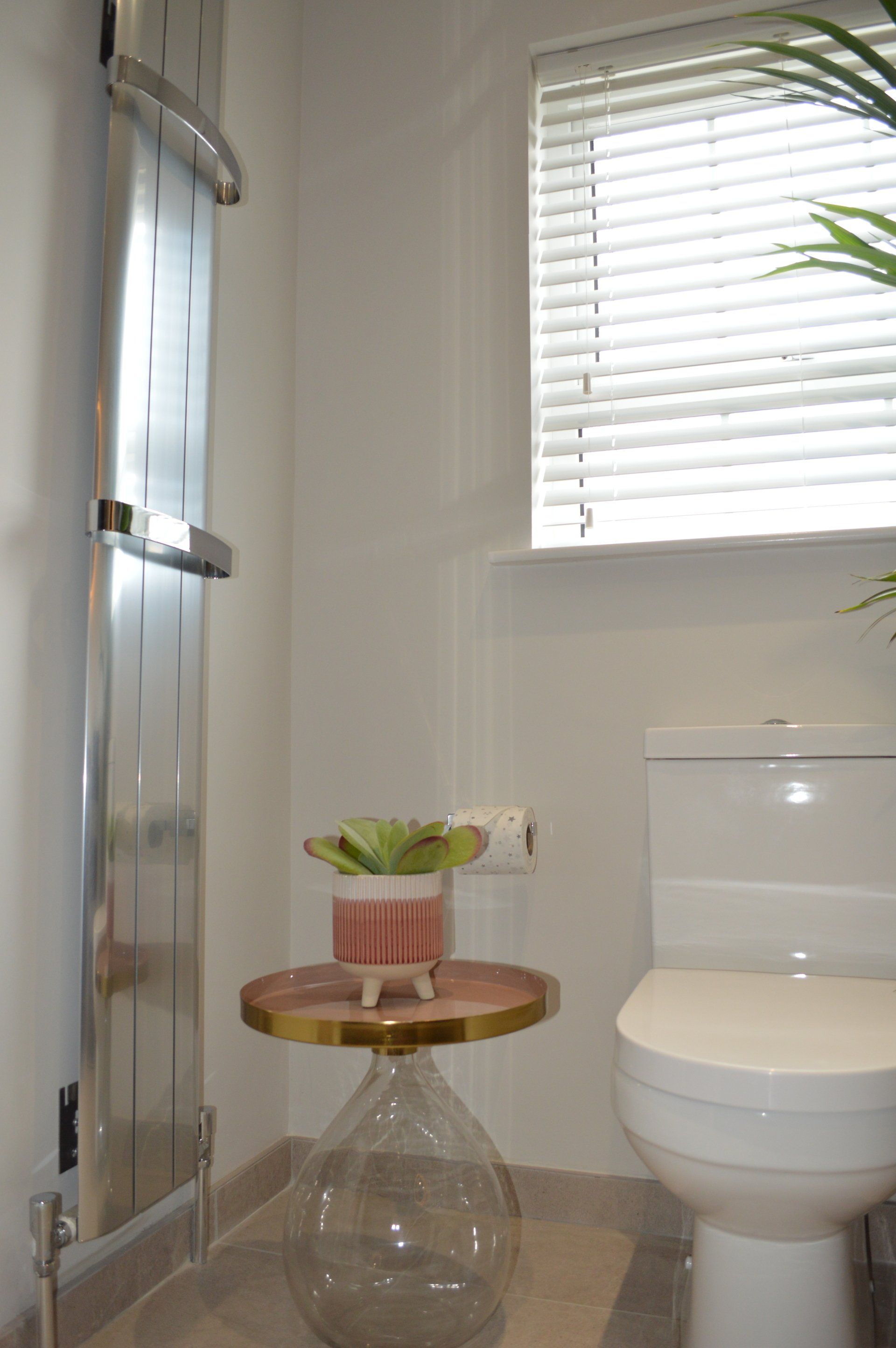 A bathroom with a toilet and a table with a plant on it.