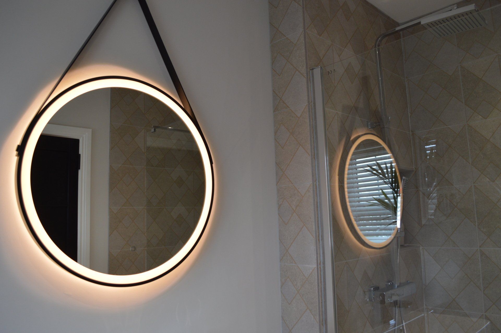 A bathroom with a round mirror and a shower stall