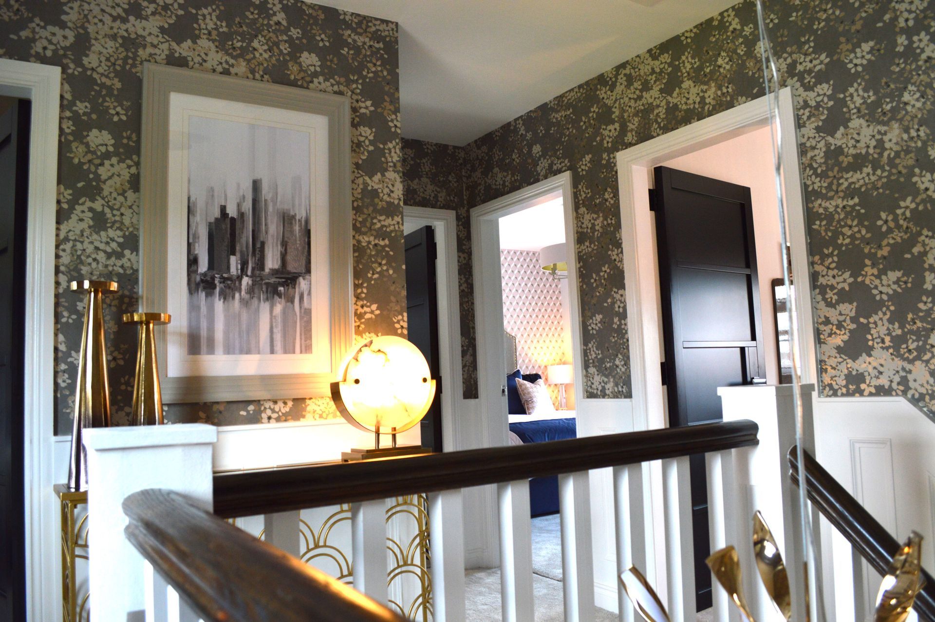 A staircase with a picture on the wall and a lamp on the railing