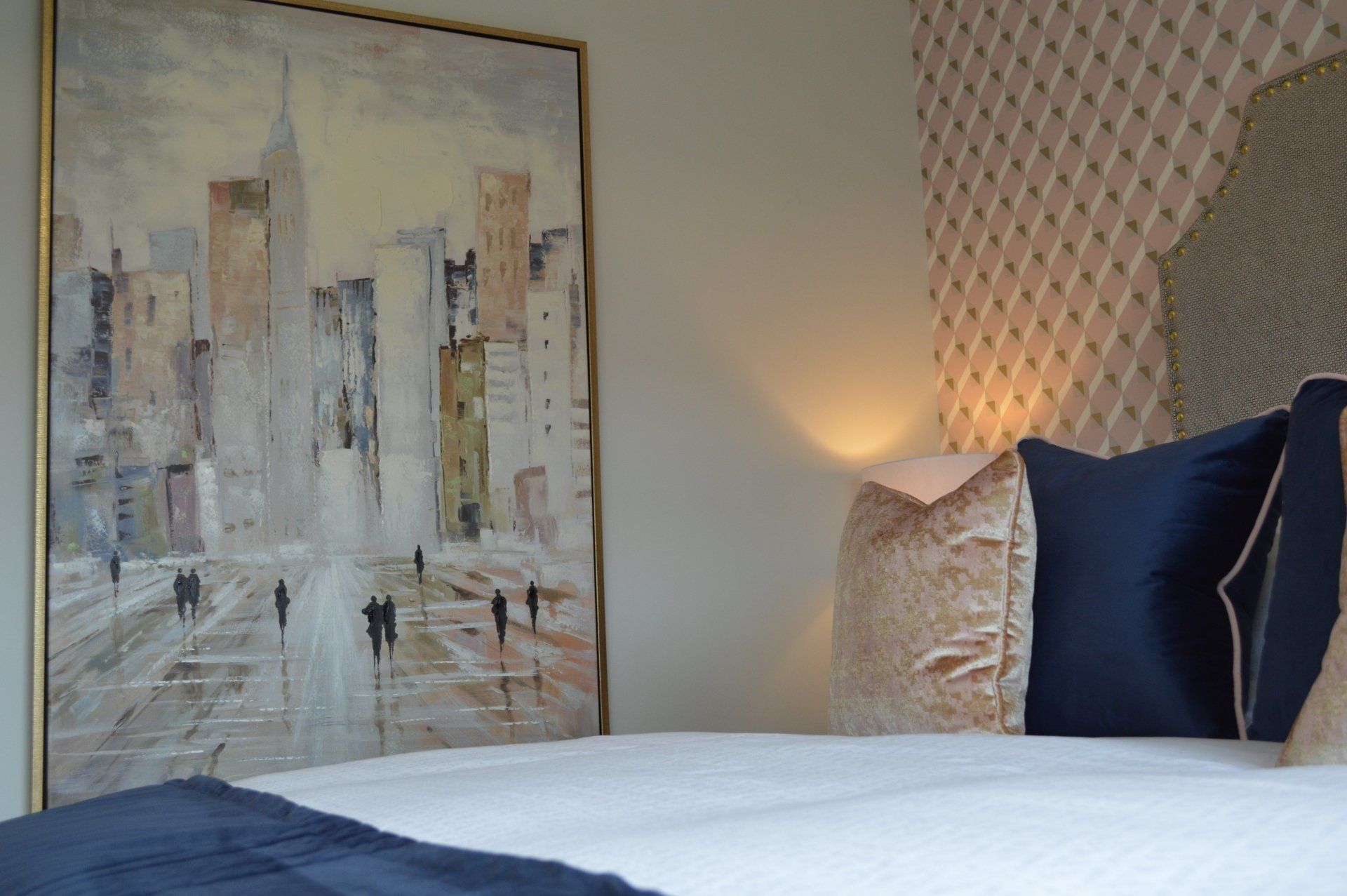 There is a painting on the wall above the bed.