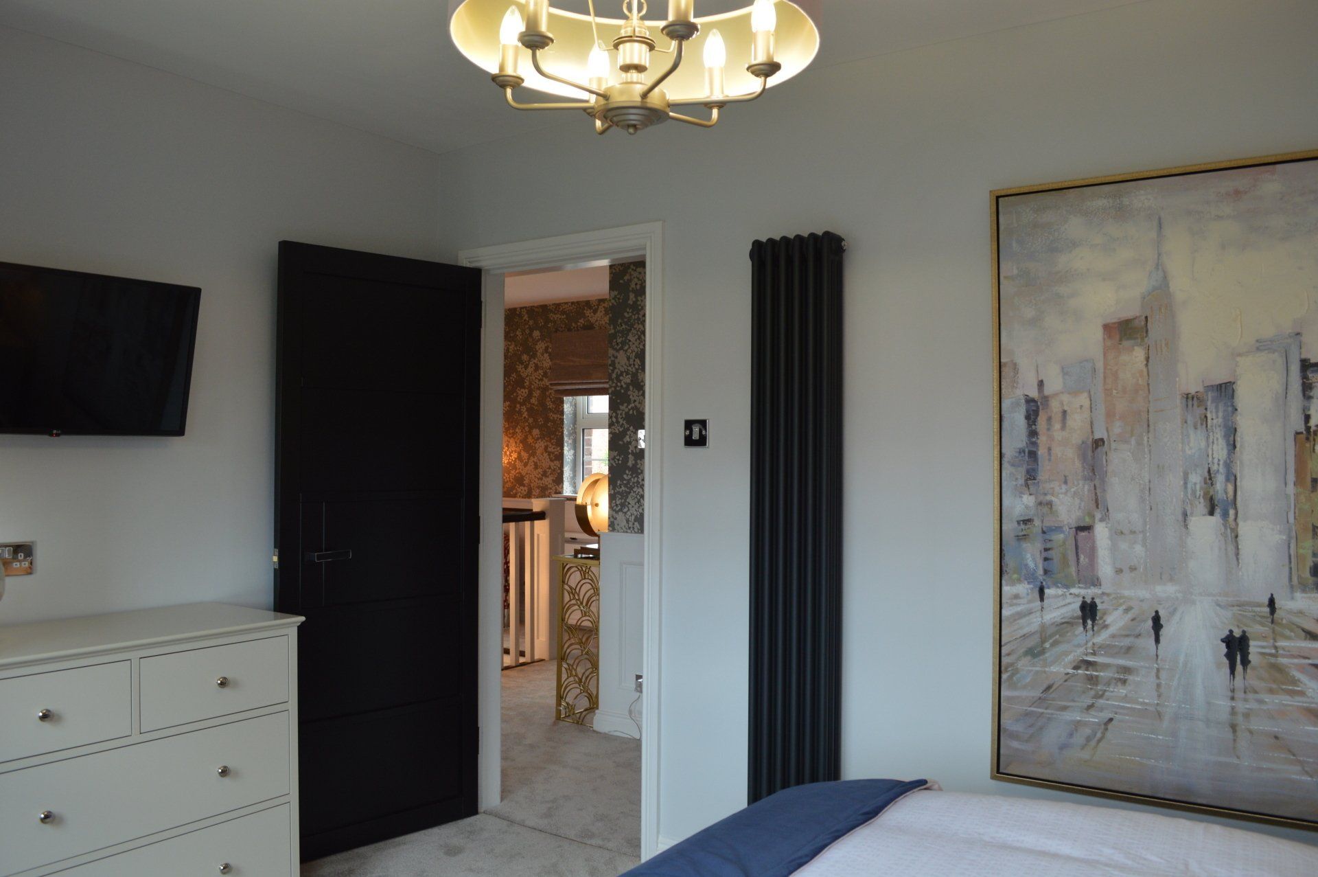 A bedroom with a bed , dresser , television and a painting on the wall.