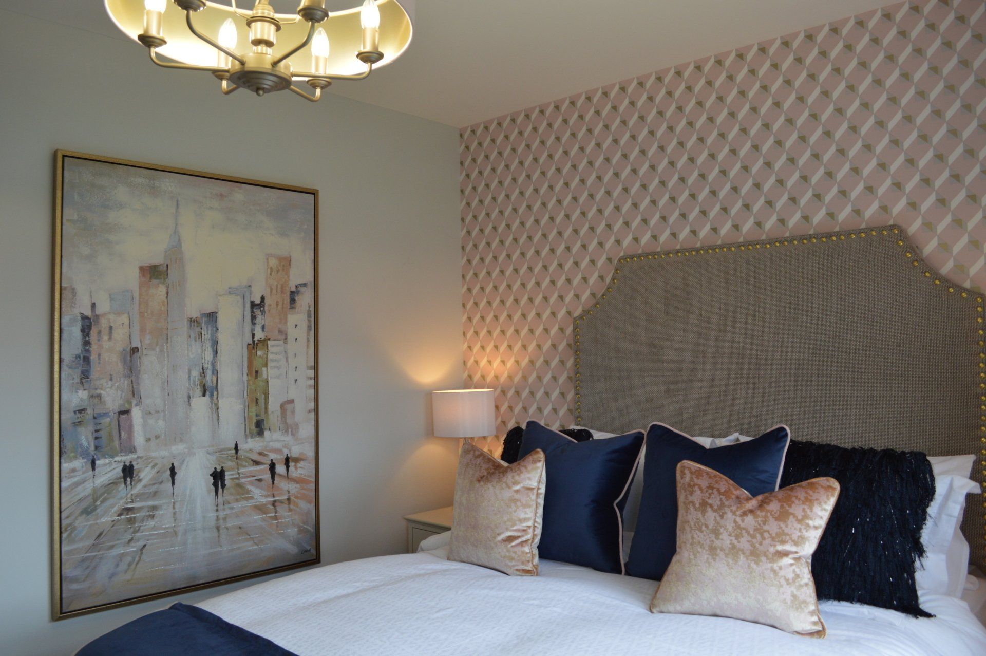 A bedroom with a large painting on the wall above the bed