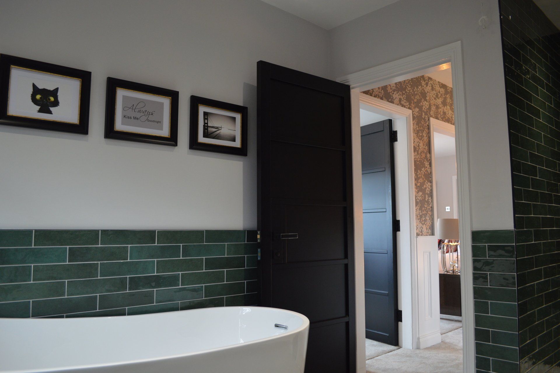 A bathroom with green tiles and a white tub
