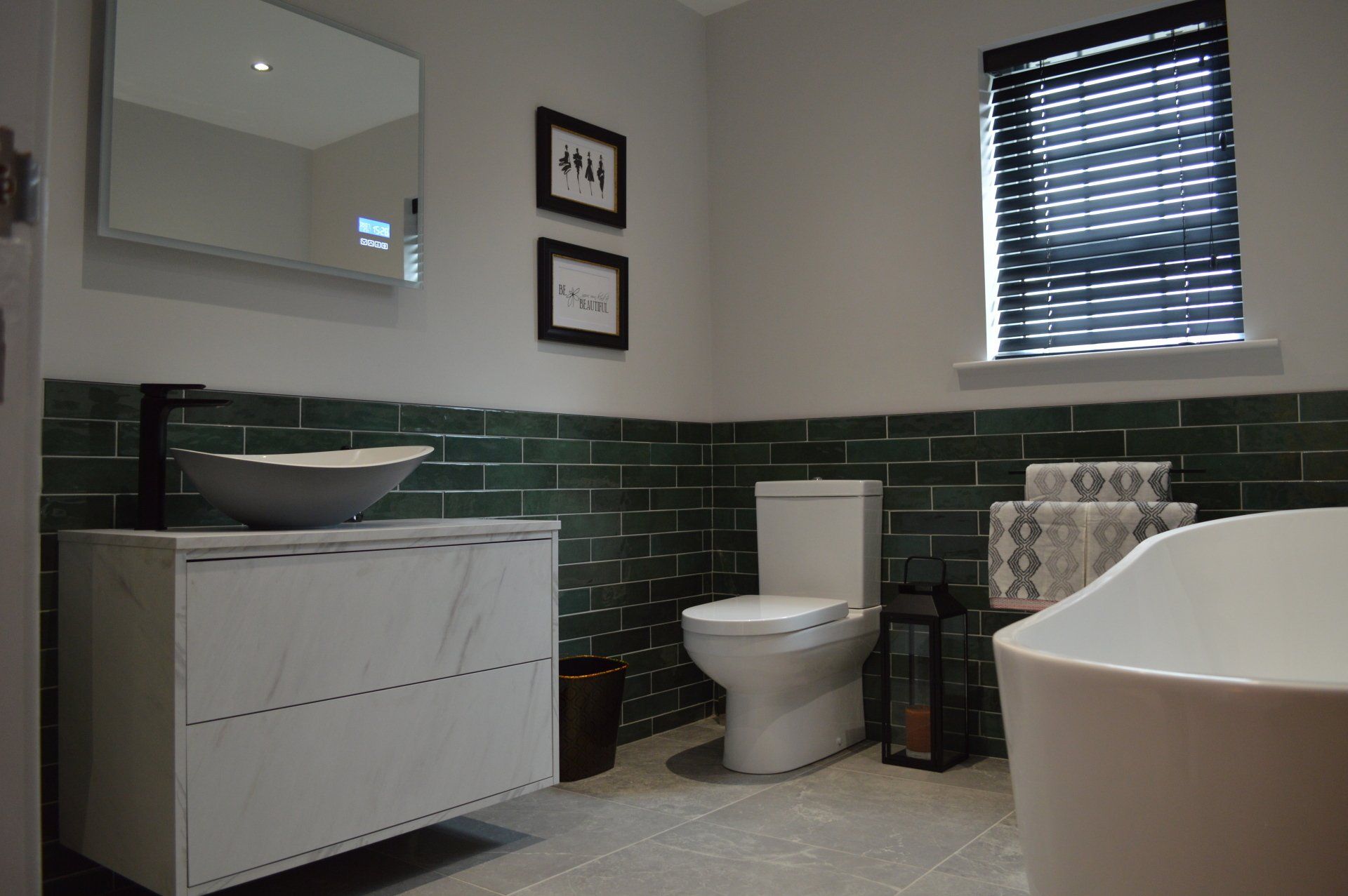 A bathroom with green tiles , a sink , toilet , and bathtub.