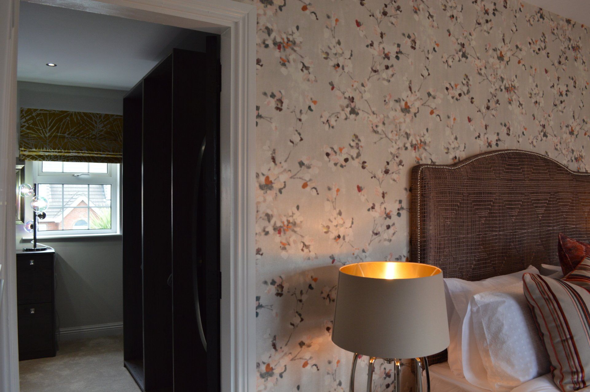 A bedroom with a bed , lamp , and wardrobe.