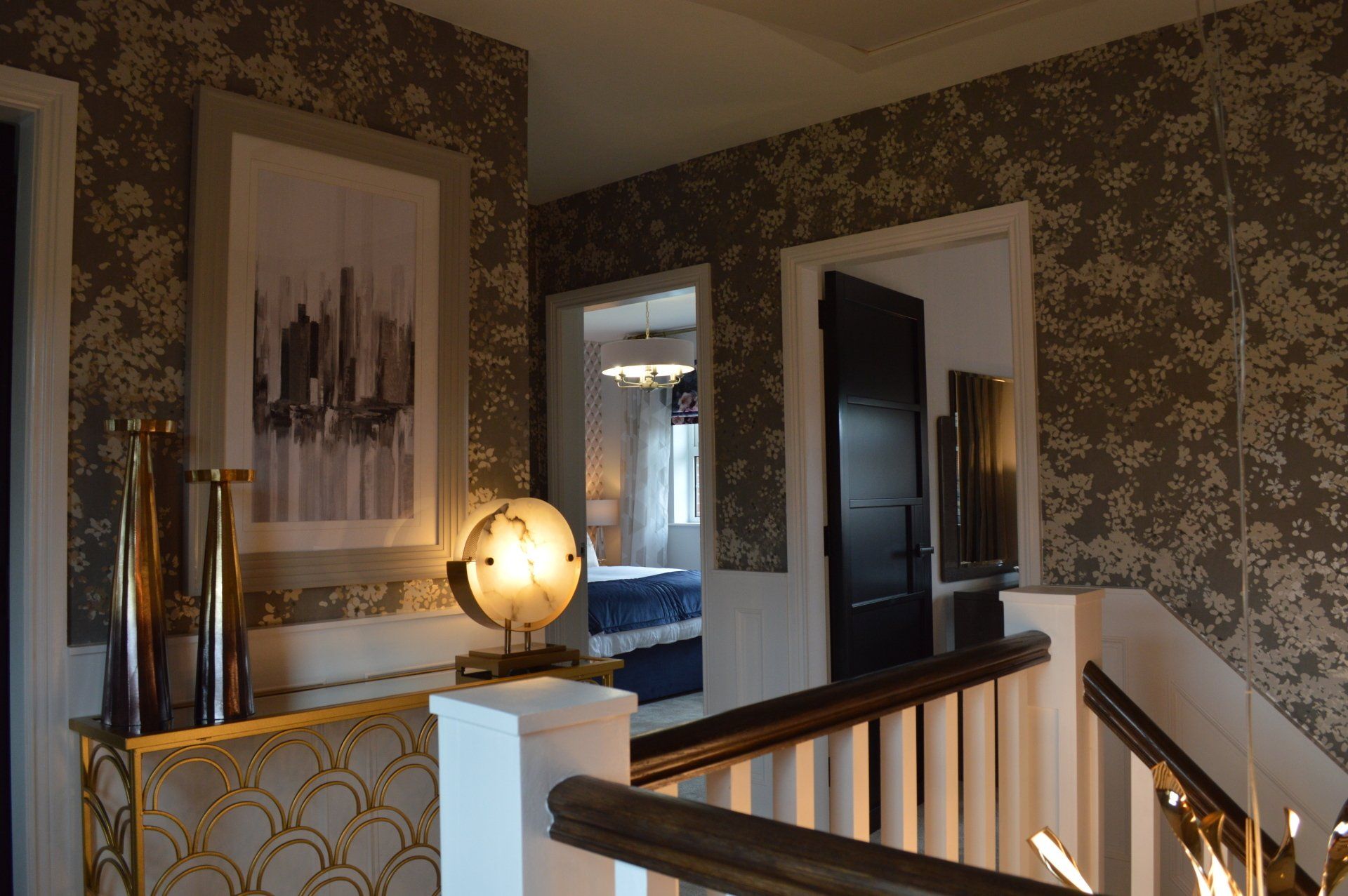 A staircase with a picture on the wall and a lamp on the railing.