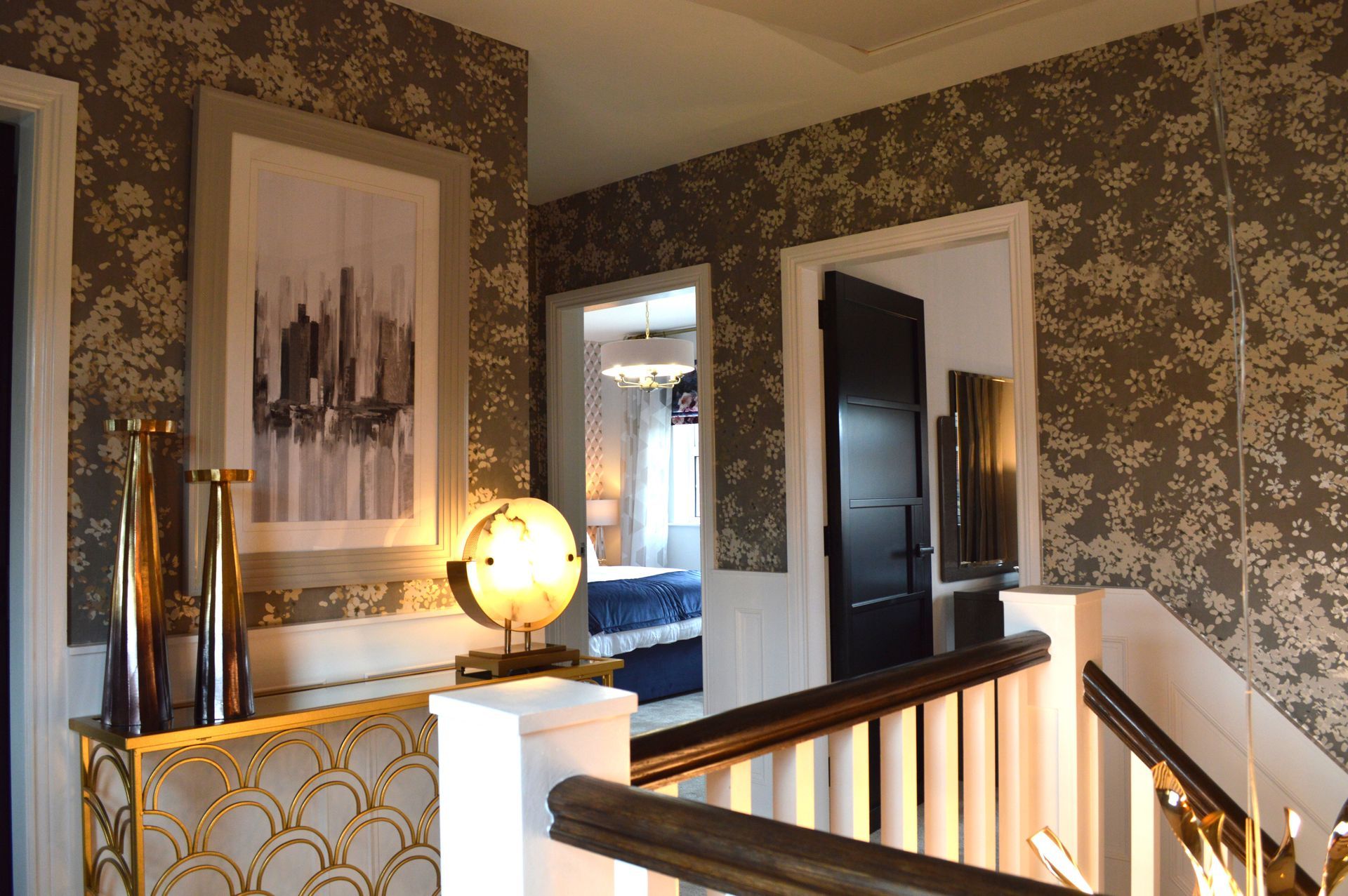 A hallway in a house with a staircase and a mirror.