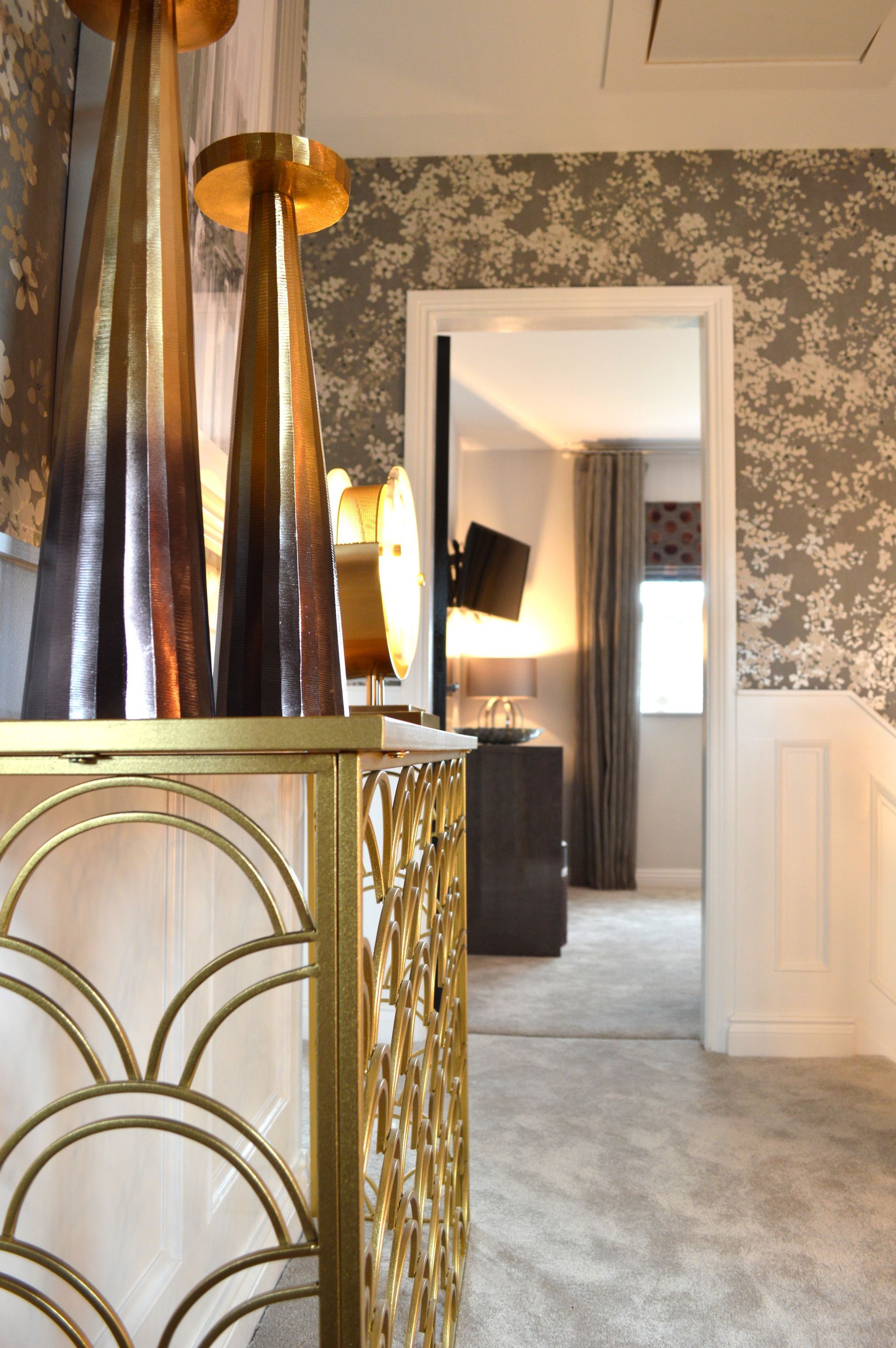 A hallway in a house with a gold table and lamps.