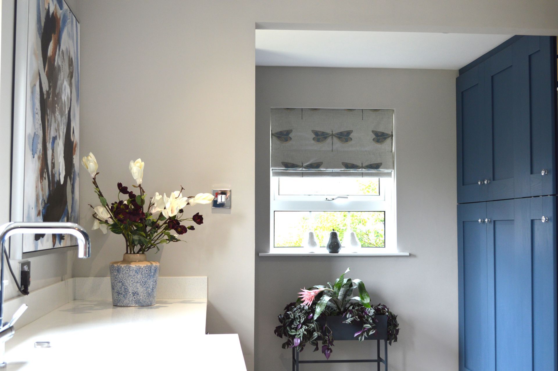 A bathroom with blue cabinets and a vase of flowers on the counter