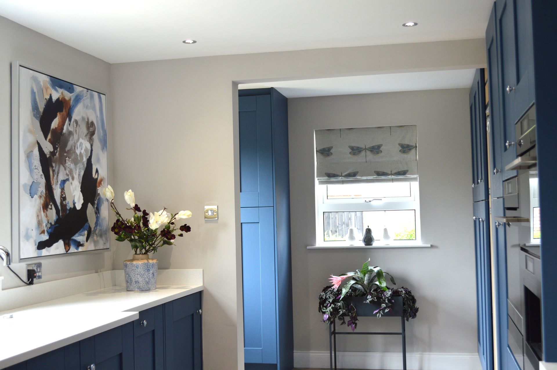 A kitchen with blue cabinets and white counter tops.