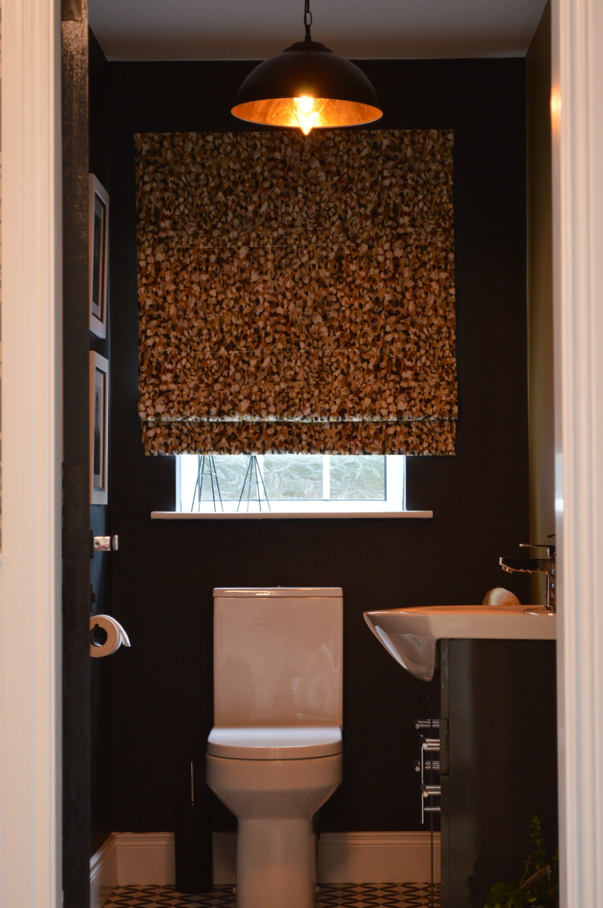 A bathroom with a toilet , sink and window.