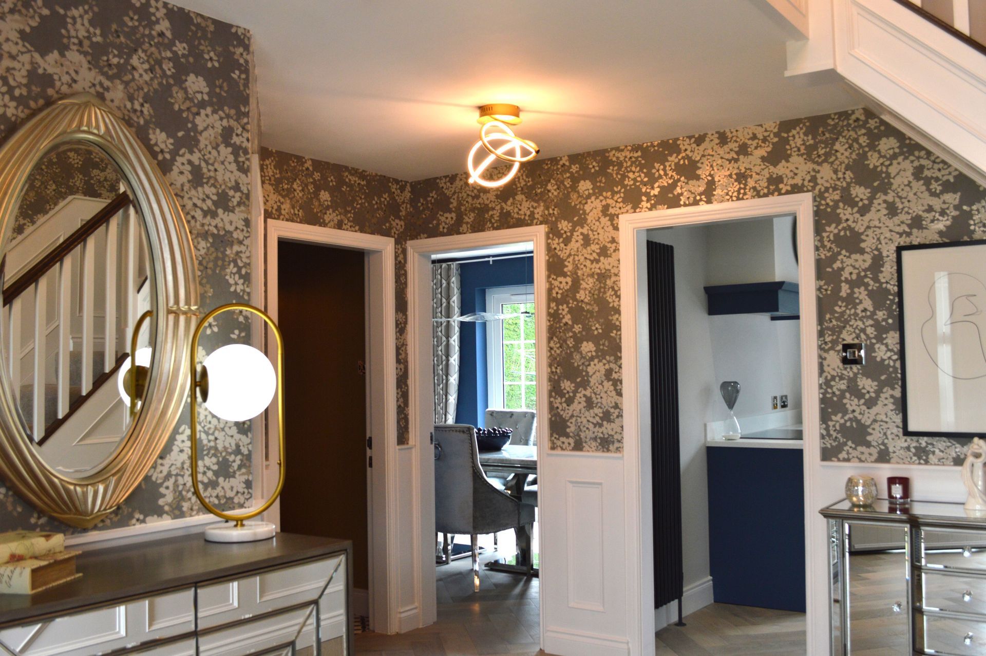 A hallway in a house with a mirror and stairs.