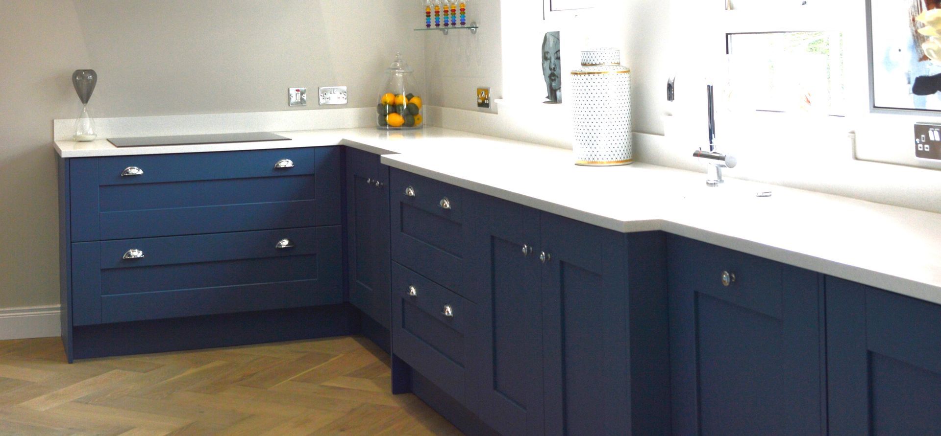 A kitchen with blue cabinets and white counter tops.