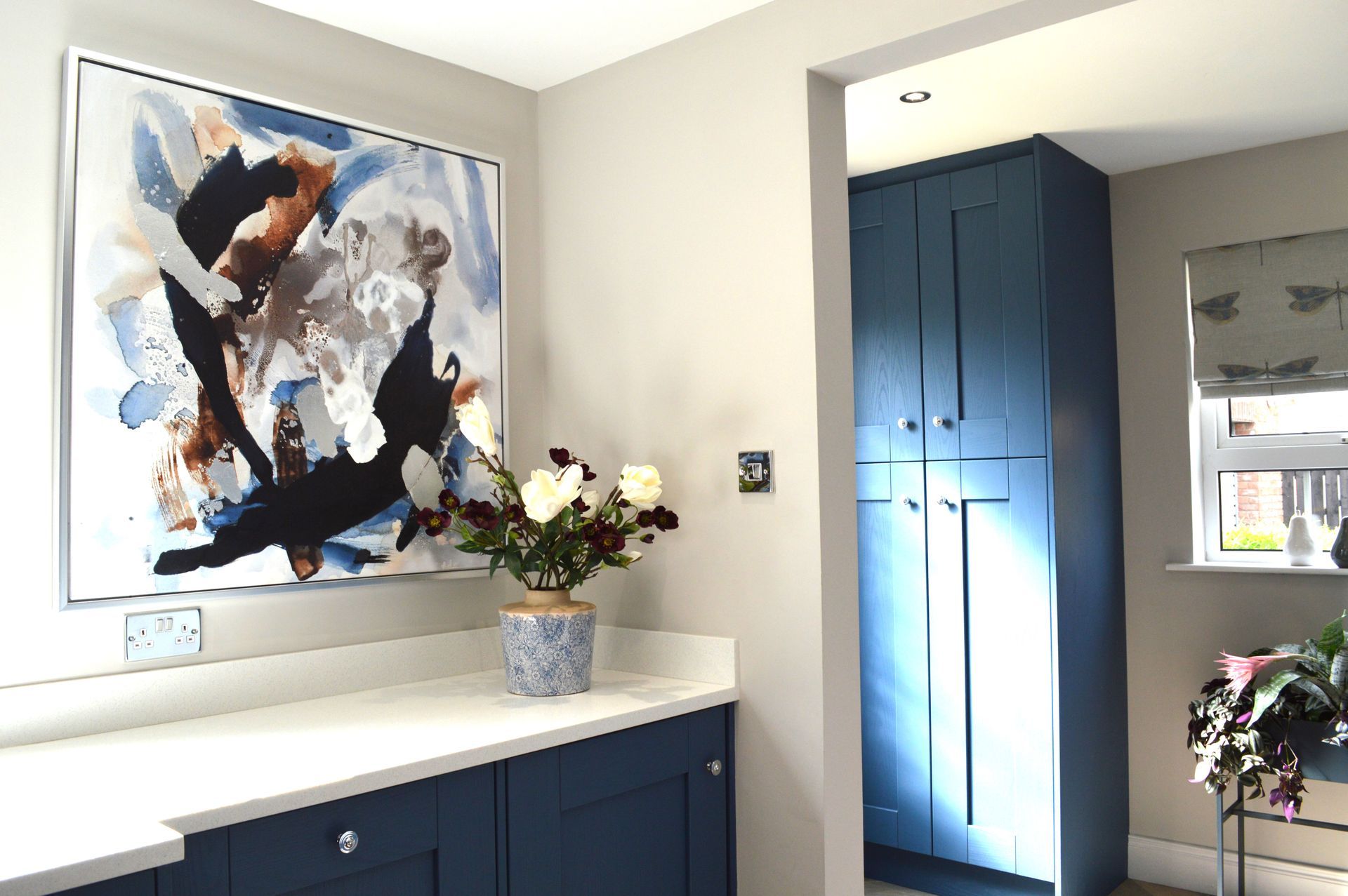 A kitchen with blue cabinets and a painting on the wall.
