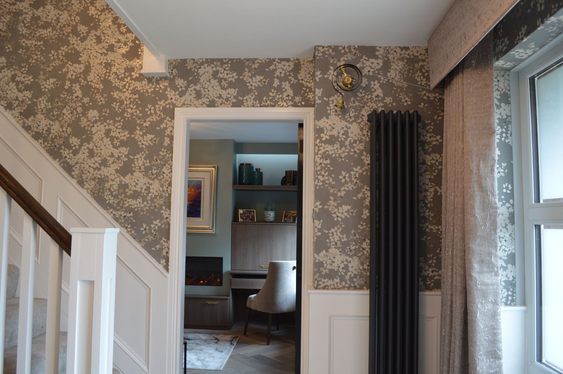 A hallway with a table and lamps in the foreground and a doorway in the background.
