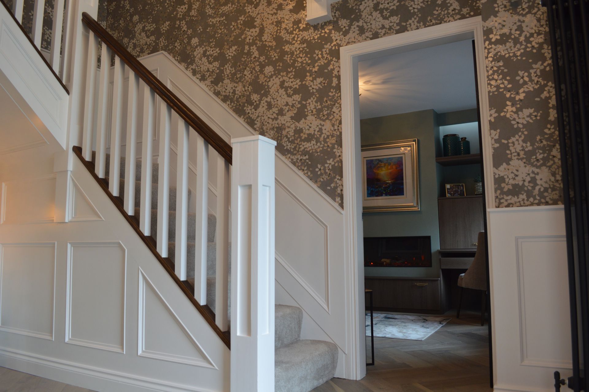 A staircase with a wooden railing in a hallway leading to a living room.