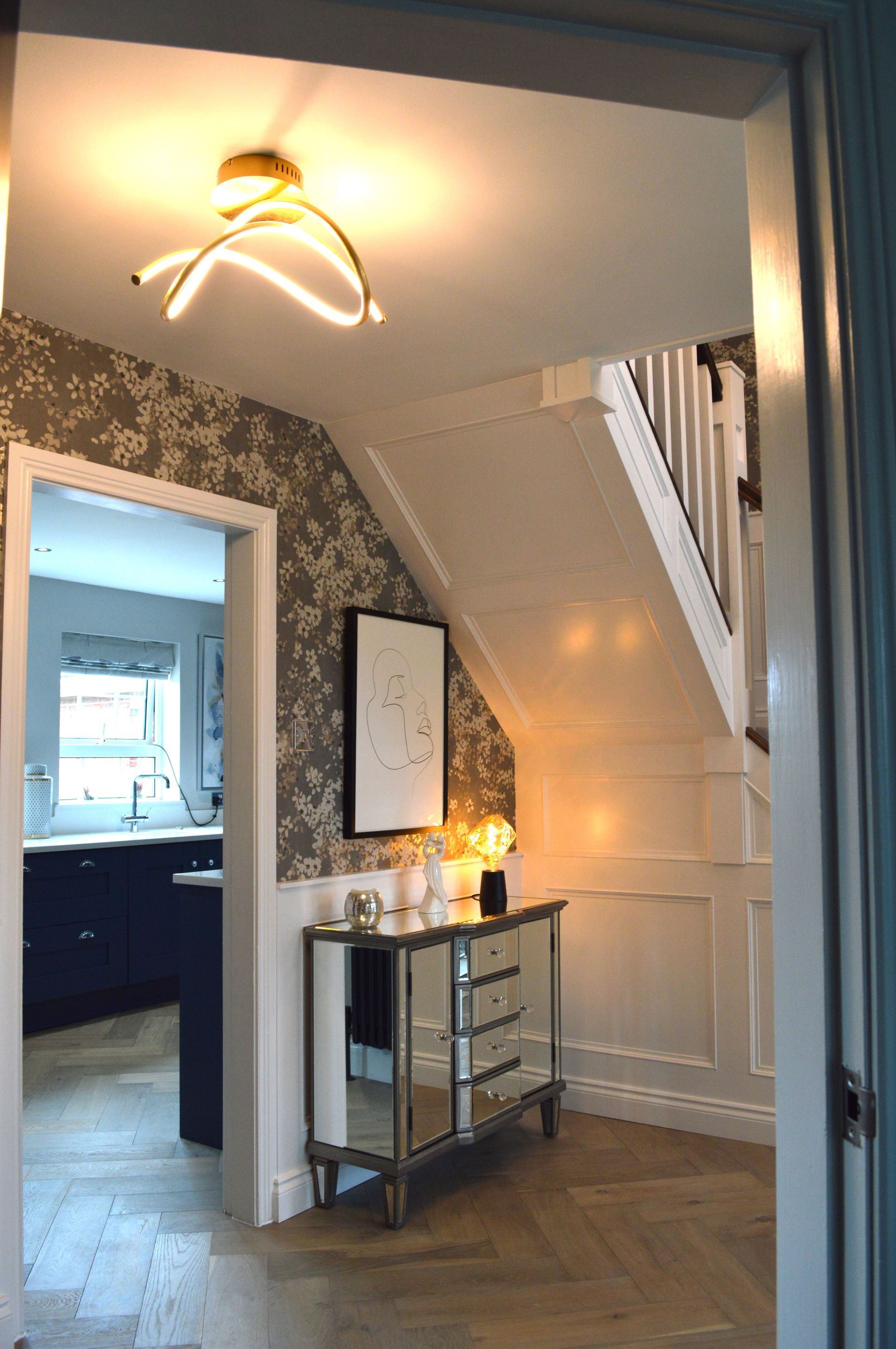 A hallway with a dresser and a staircase in the background.