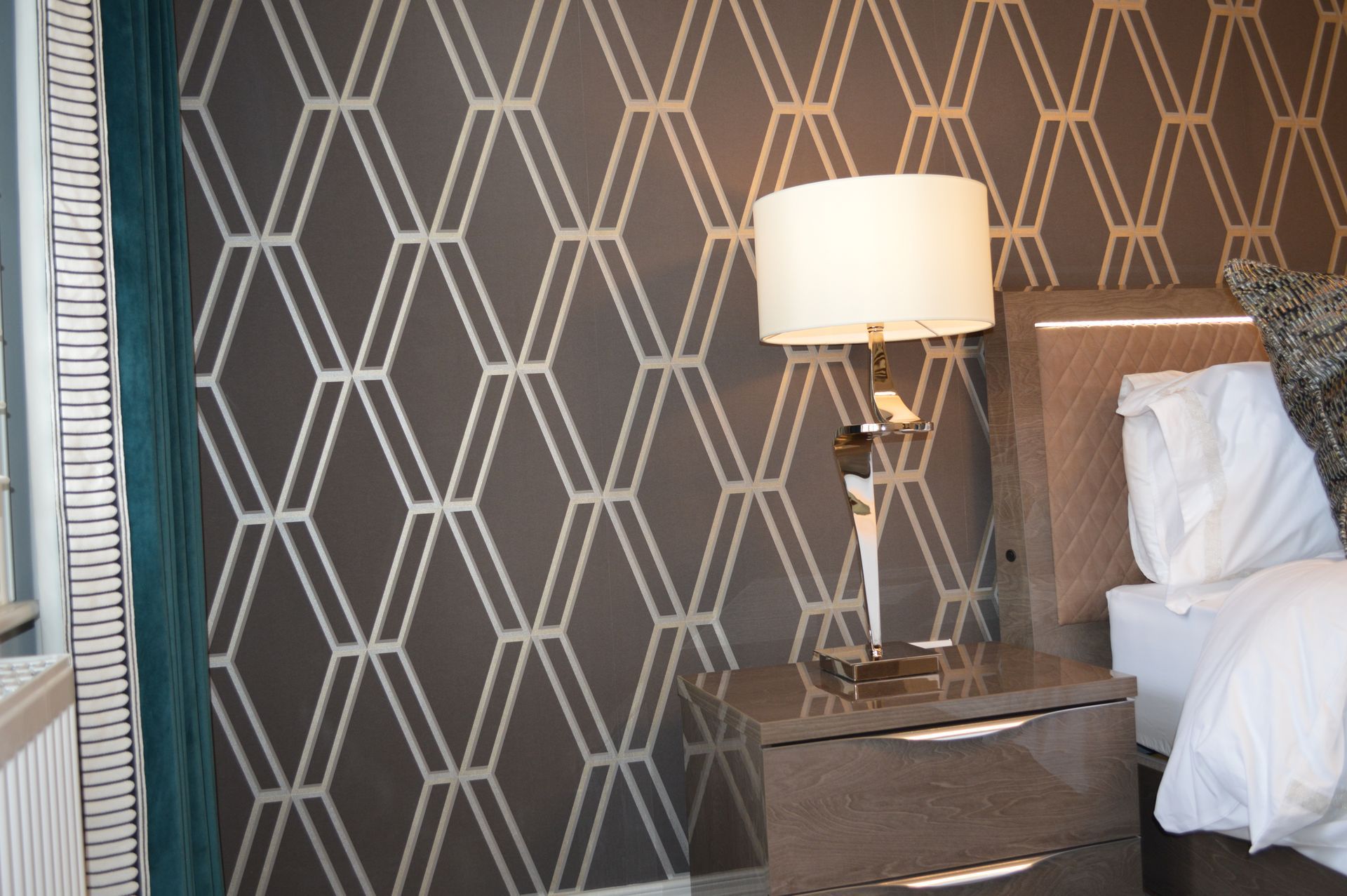 A bedroom with a bed a nightstand and a lamp