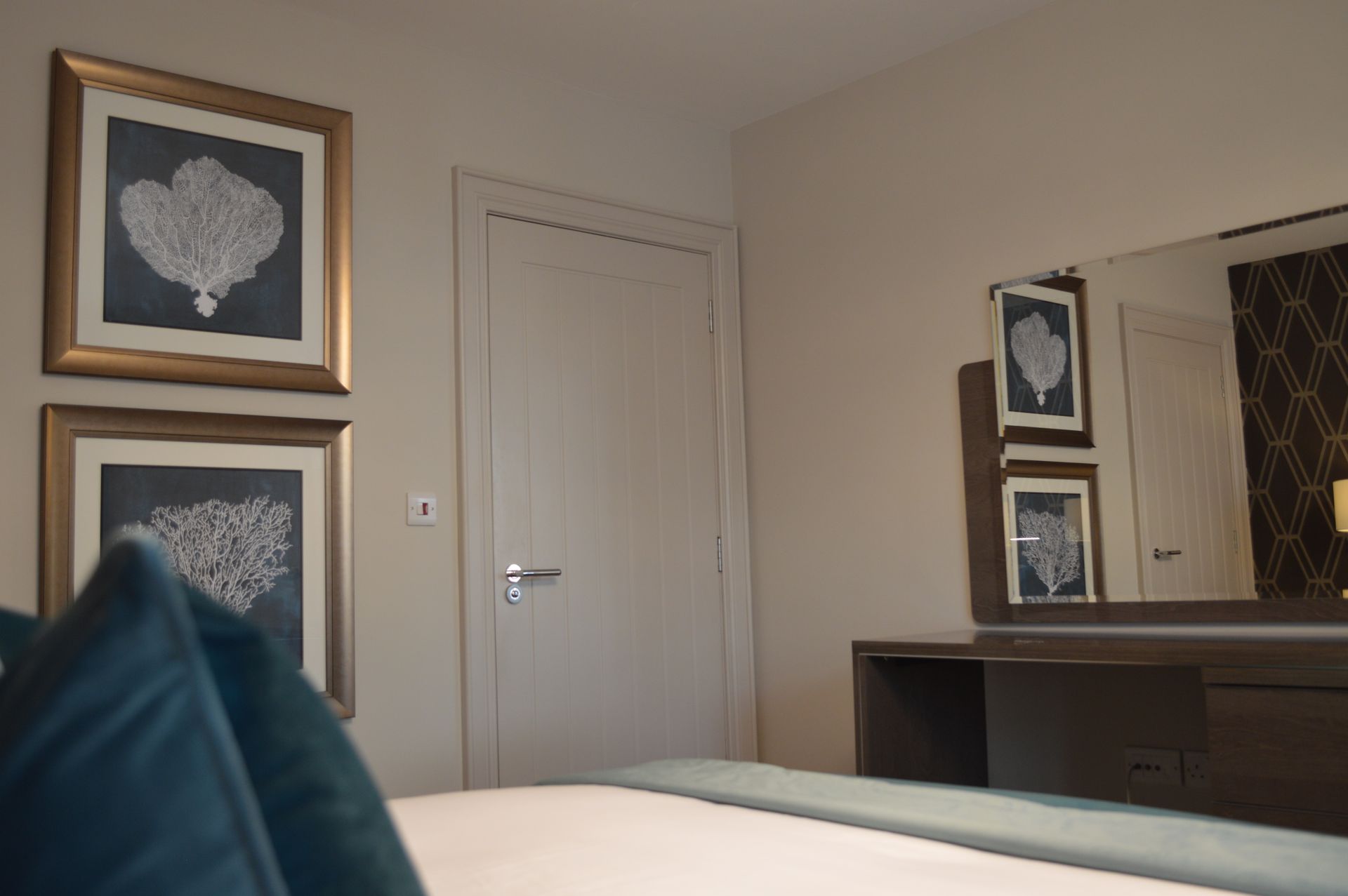 A bedroom with a bed dresser mirror and paintings on the wall