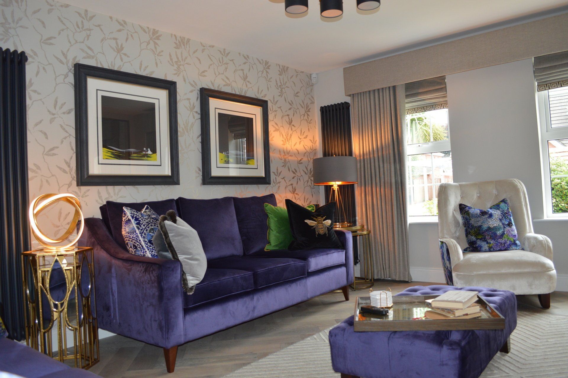A living room with a purple couch , white chair , and ottoman.
