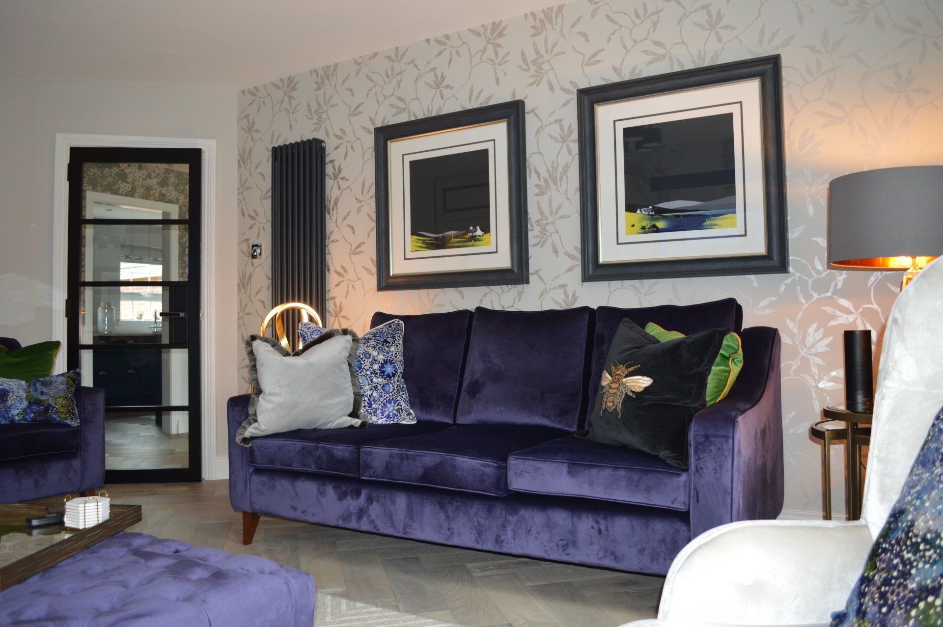 A living room with a purple couch and two paintings on the wall