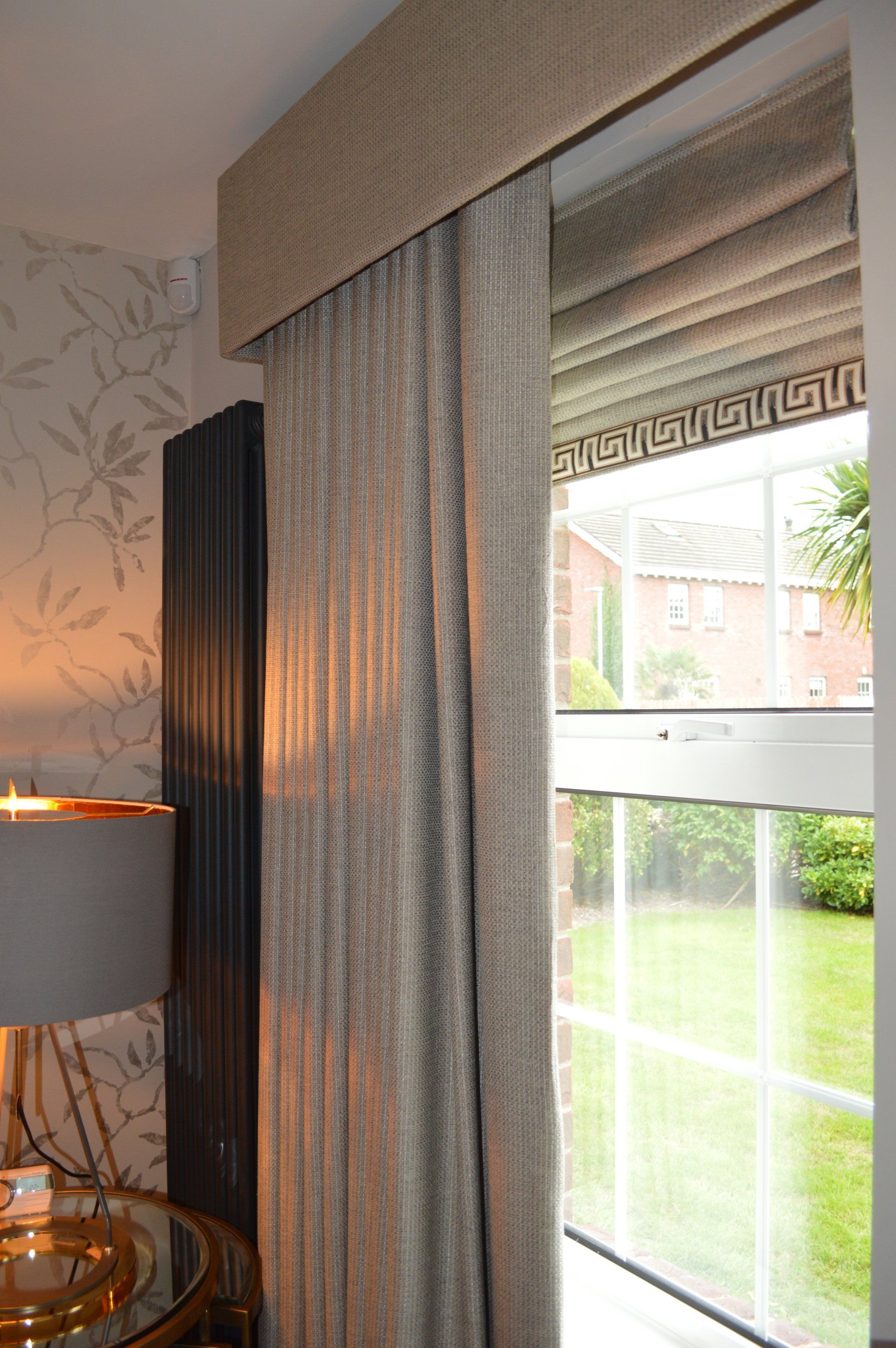 A window with curtains and a lamp in a living room.