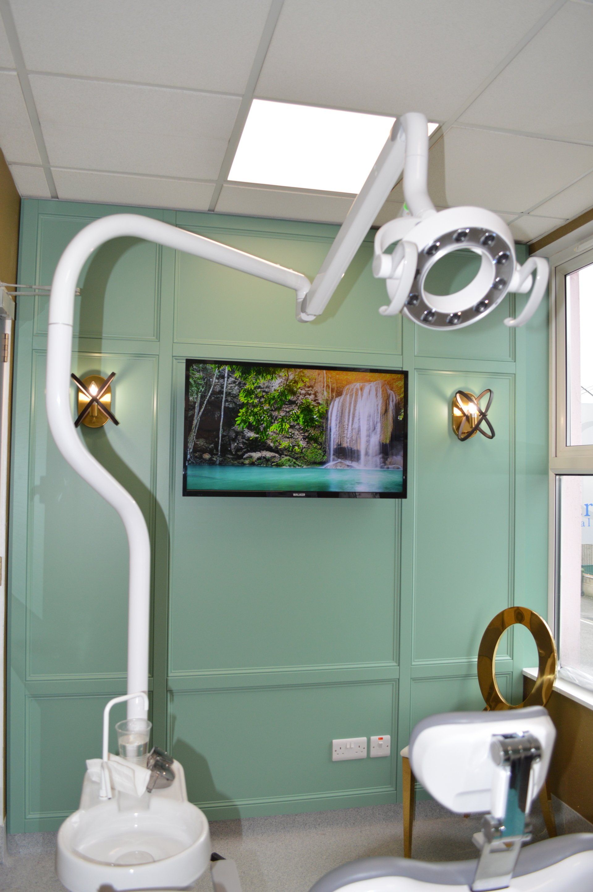 A dental office with a dental chair and a television on the wall.