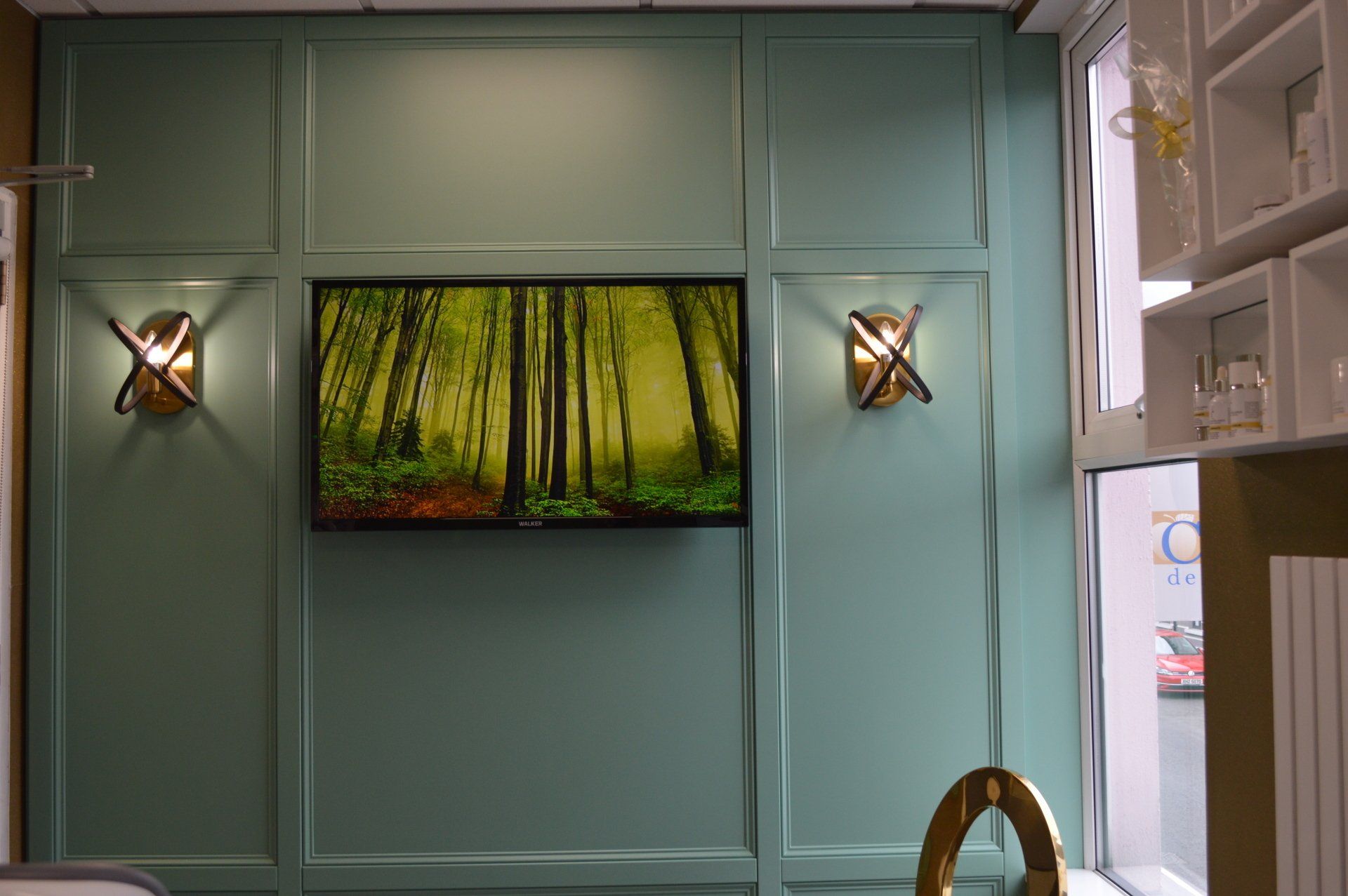 A television is hanging on a wall with a picture of a forest on it.