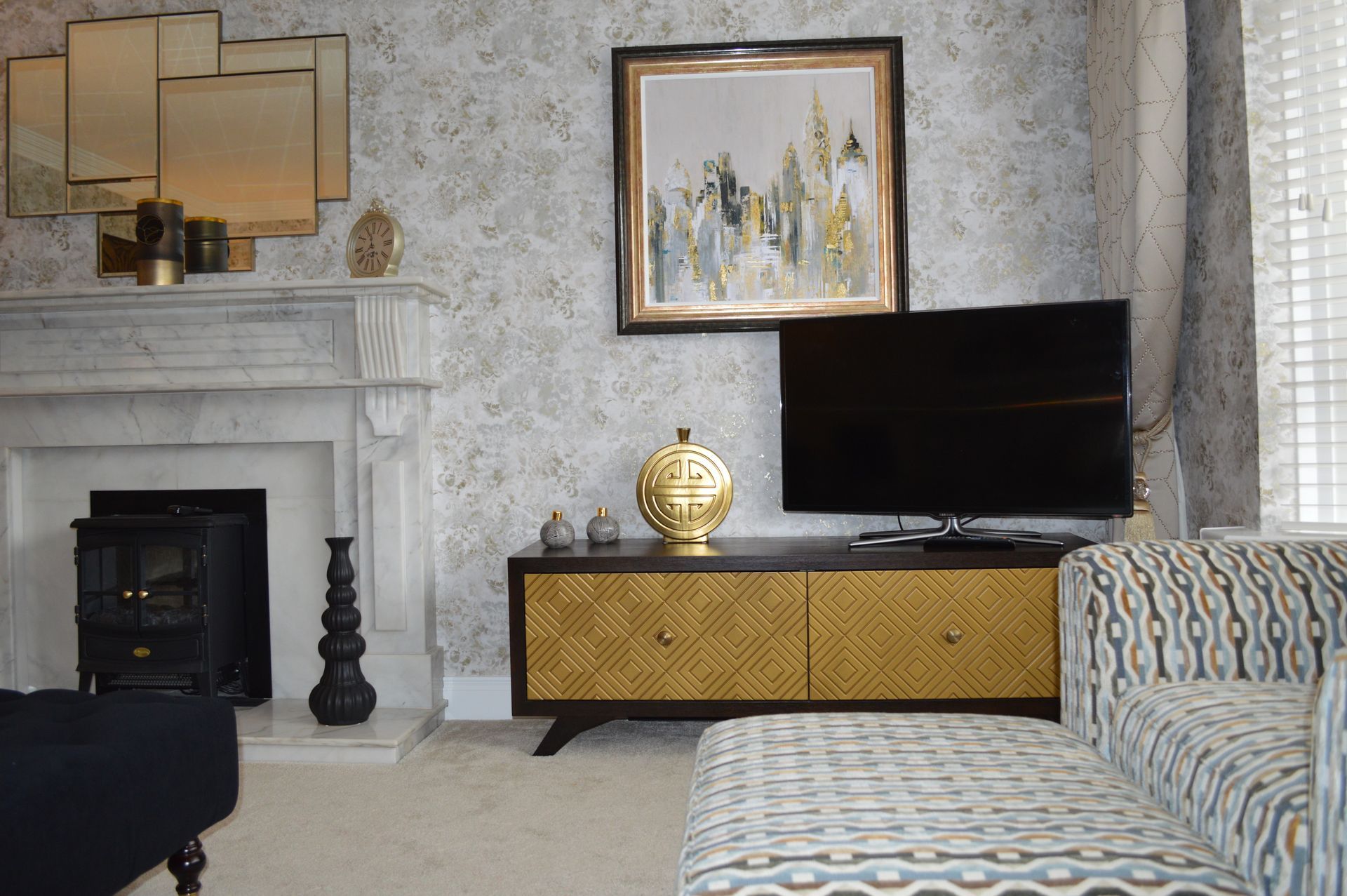 A living room with a fireplace , couch , television and a picture on the wall.