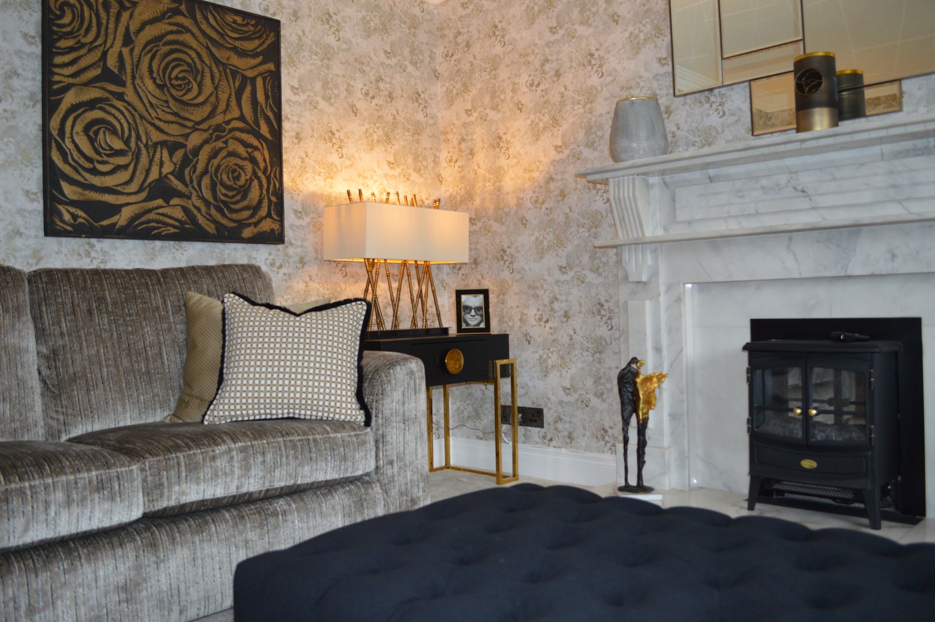 A living room with a couch , chair , ottoman and fireplace.