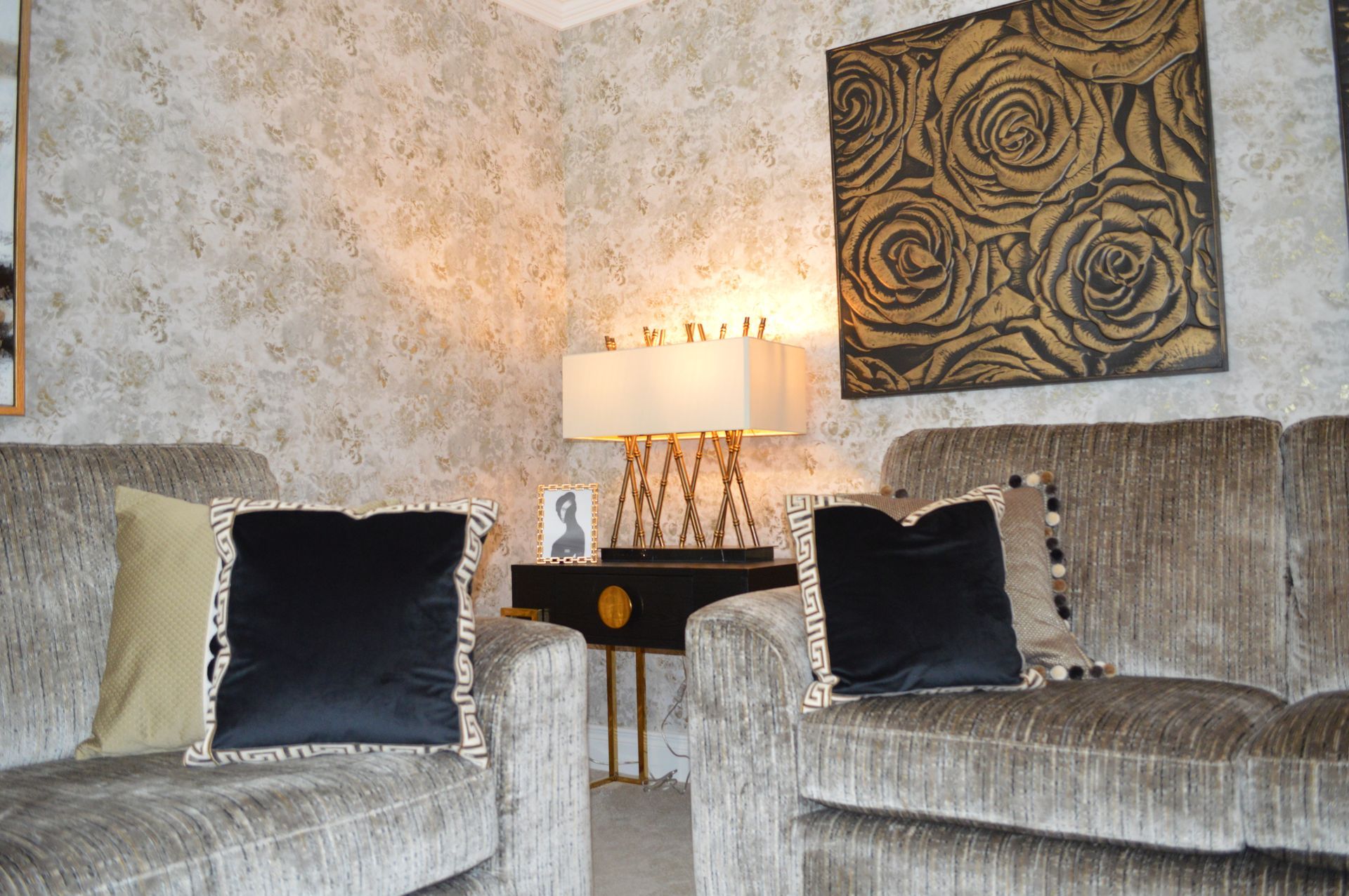 A living room with a couch and two chairs and a lamp