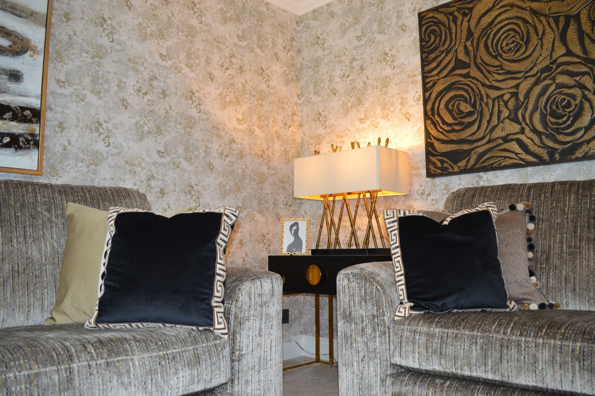 A living room with a couch and two chairs and a lamp