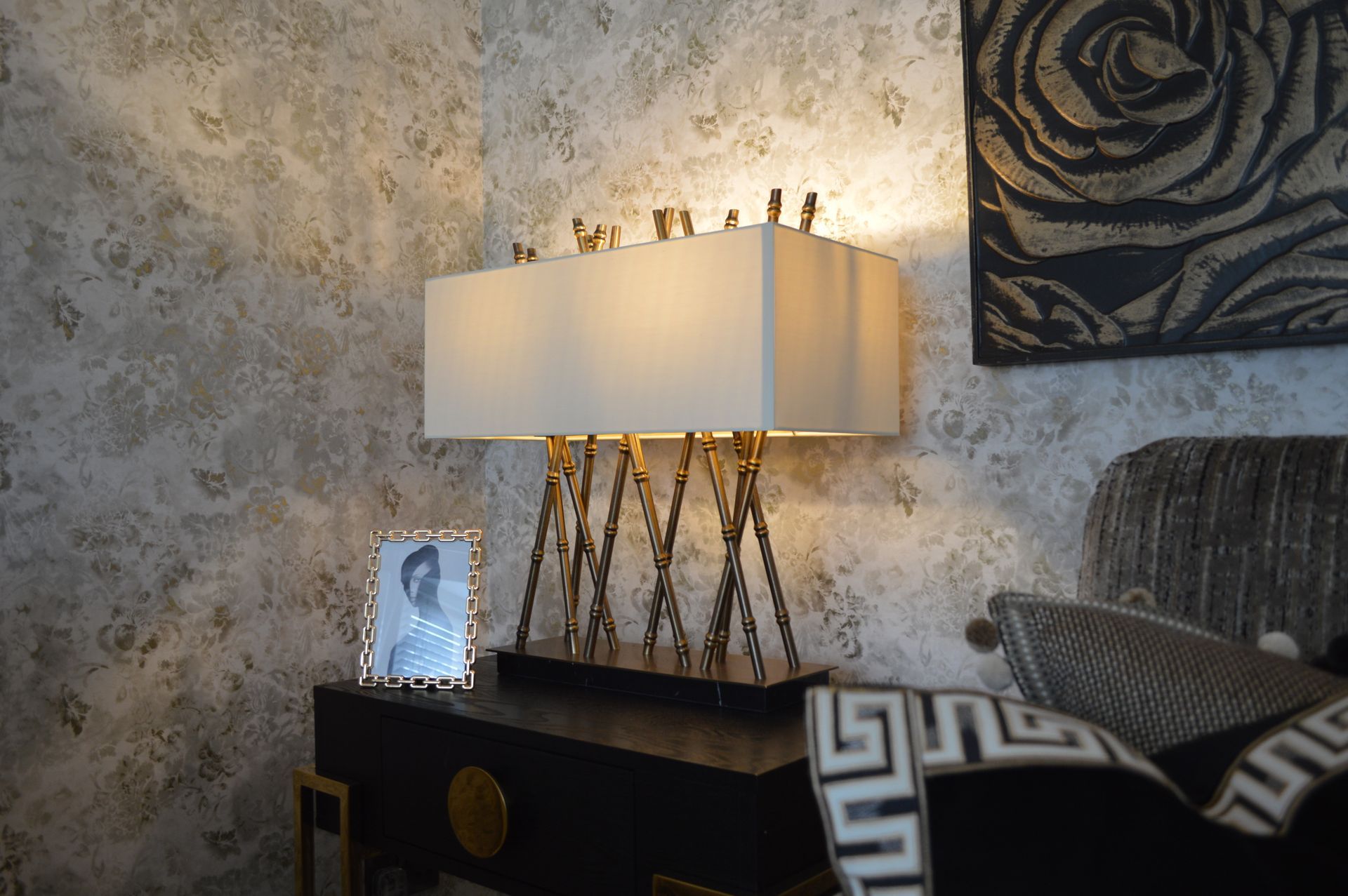 A lamp is sitting on a nightstand in a bedroom next to a bed.