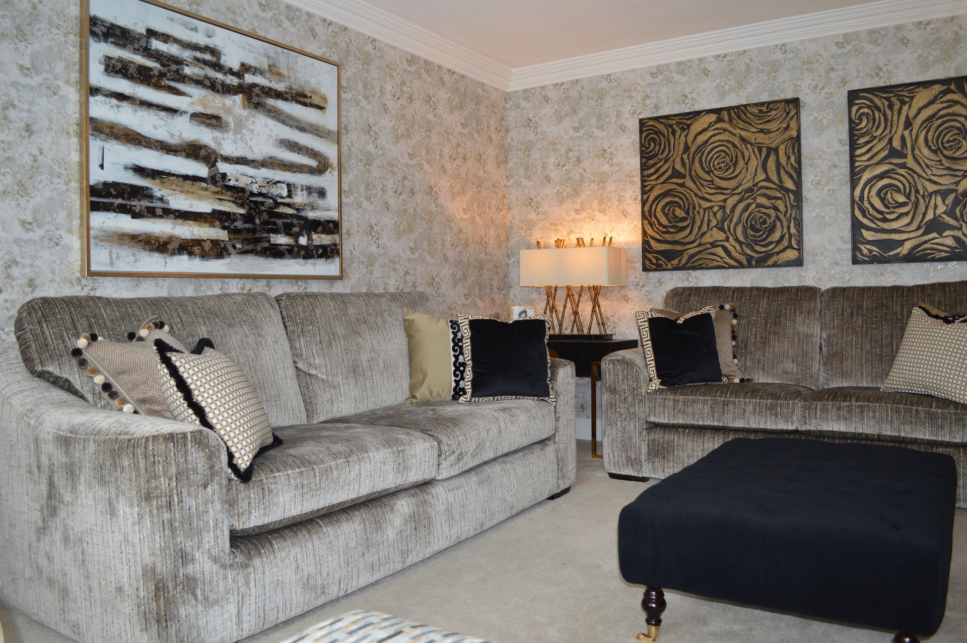 A living room with two couches , an ottoman , and a painting on the wall.