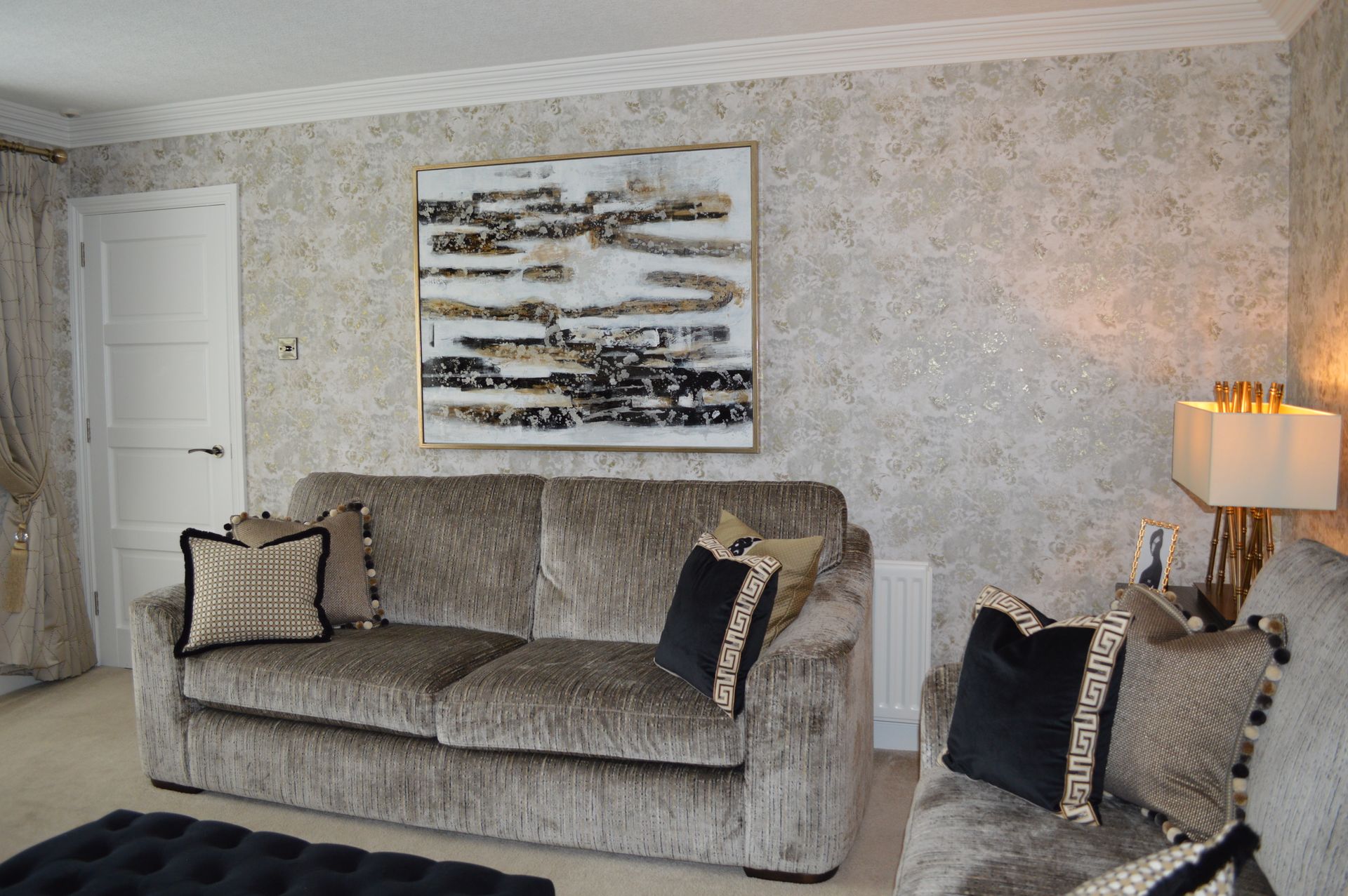 A living room with a couch , chairs , lamps and a painting on the wall.