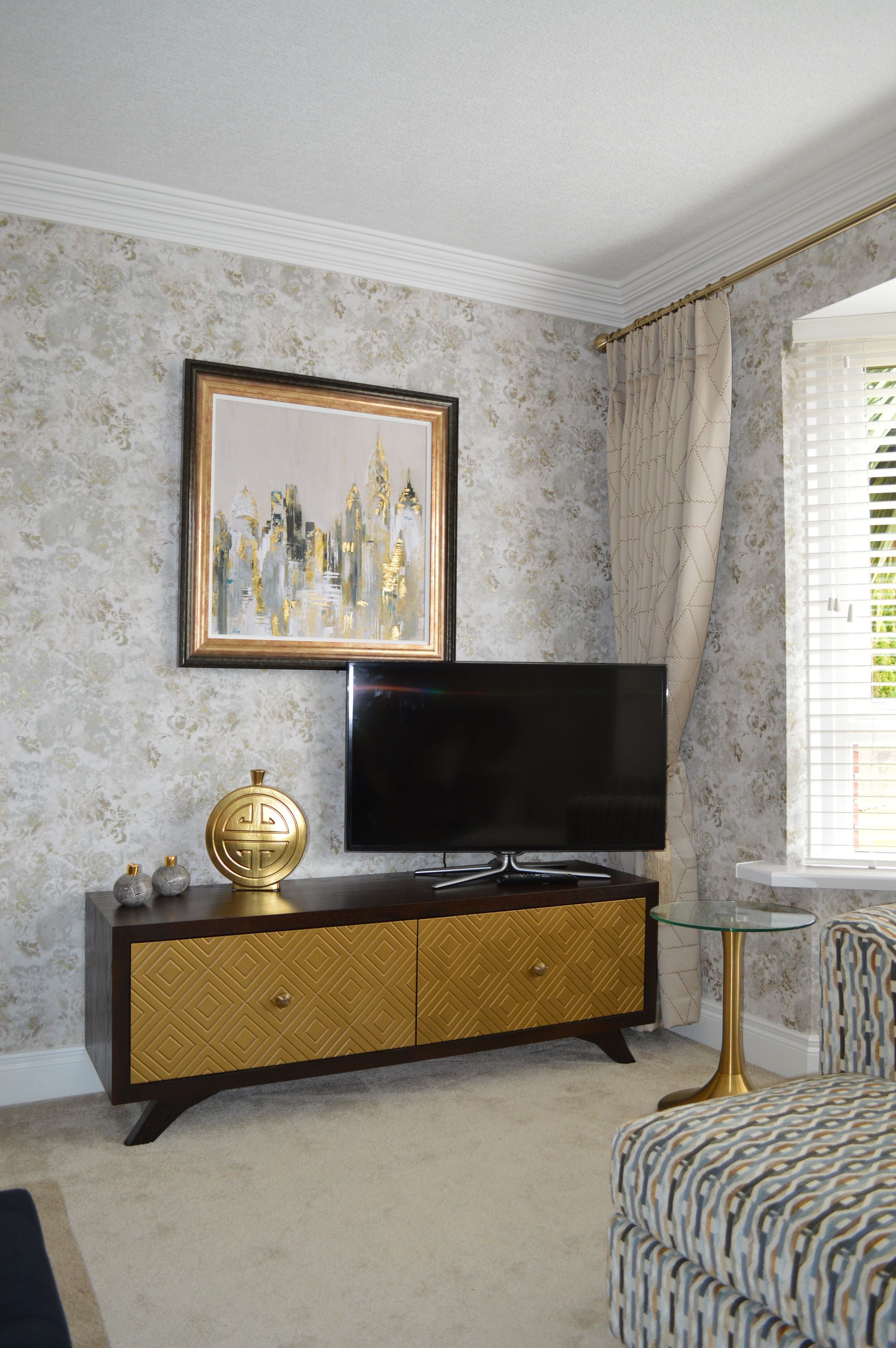 A living room with a television on a stand and a painting on the wall.