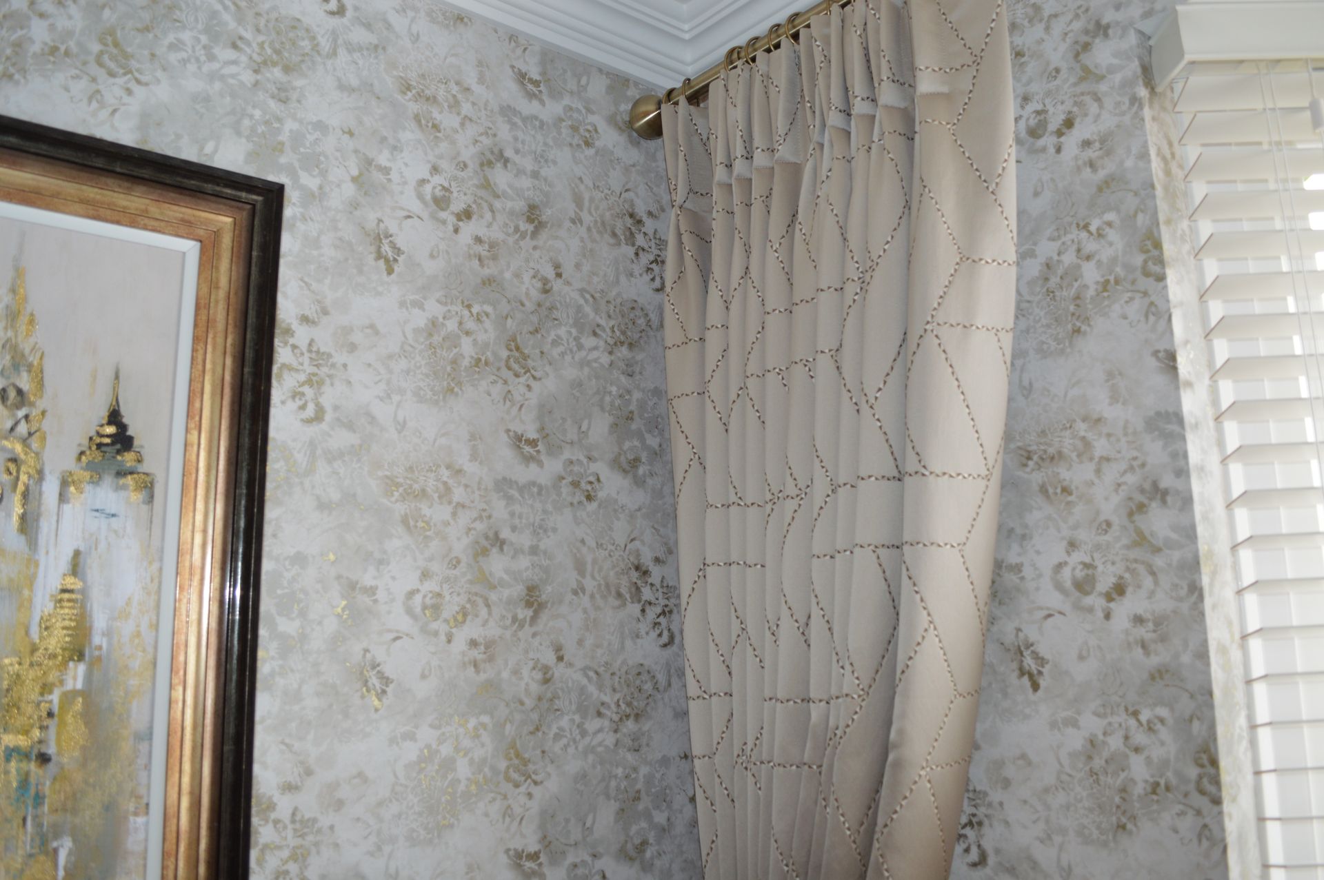 A room with a painting on the wall and curtains