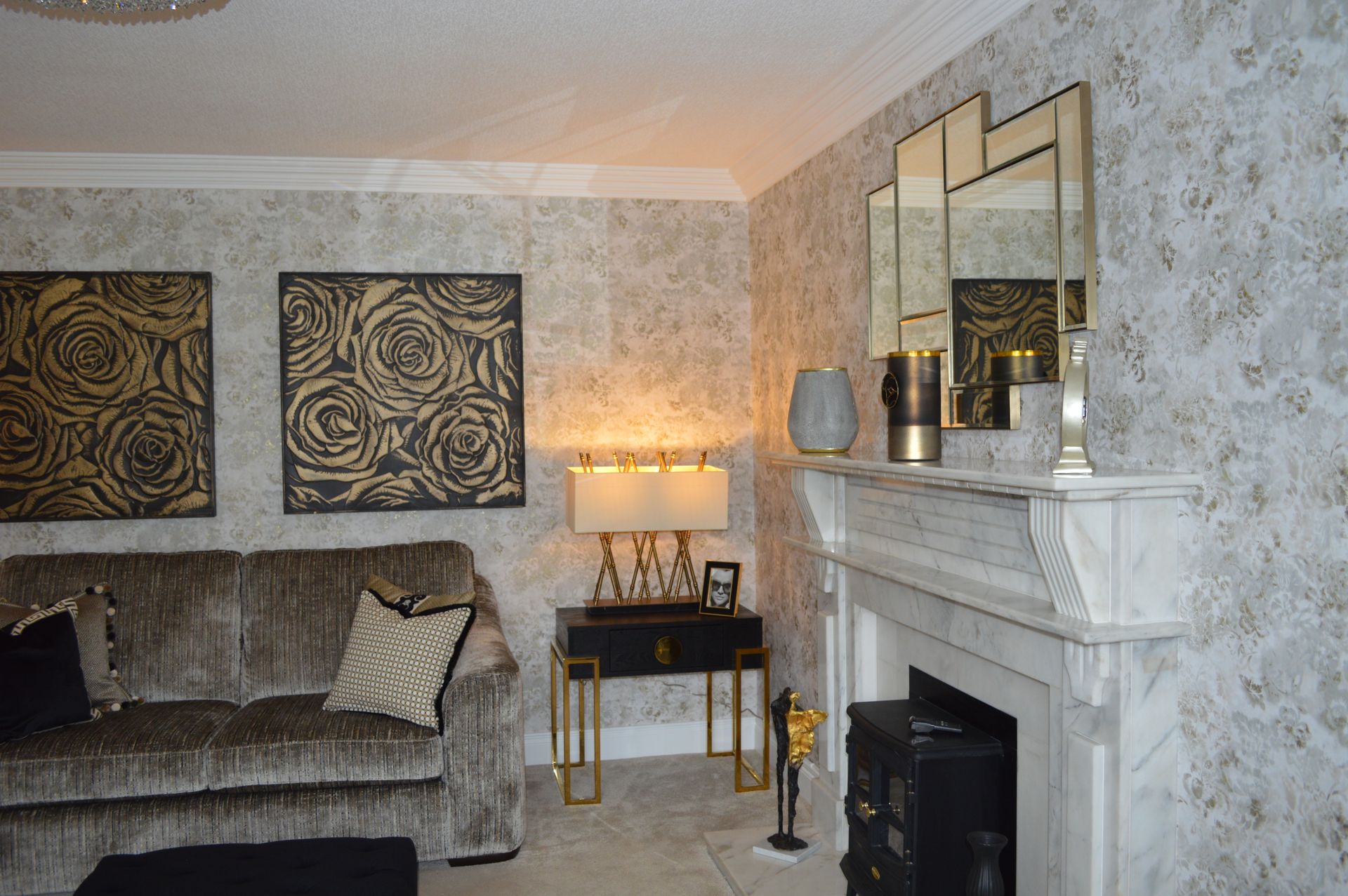A living room with a couch , fireplace , mirrors and lamps.