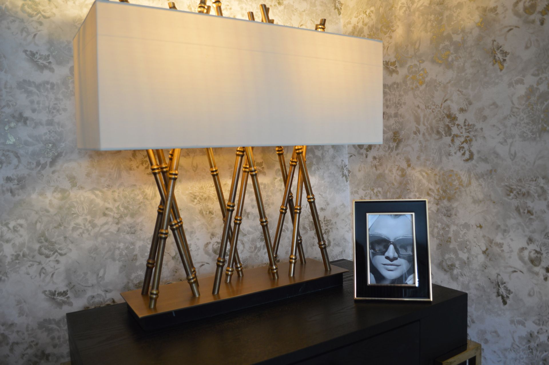 A lamp is sitting on a table next to a picture of a man wearing sunglasses.