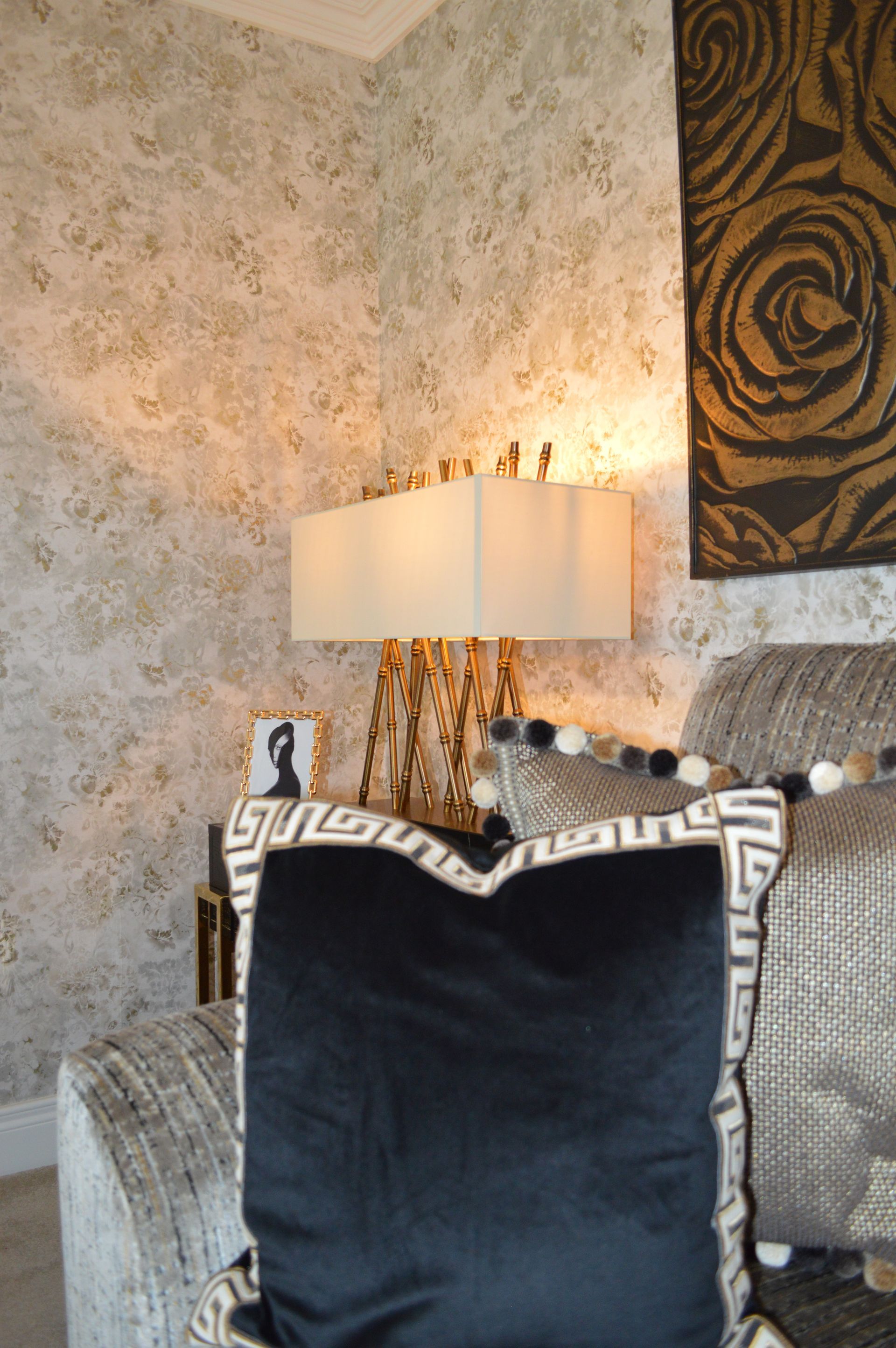 A black and white pillow sits on a couch next to a lamp