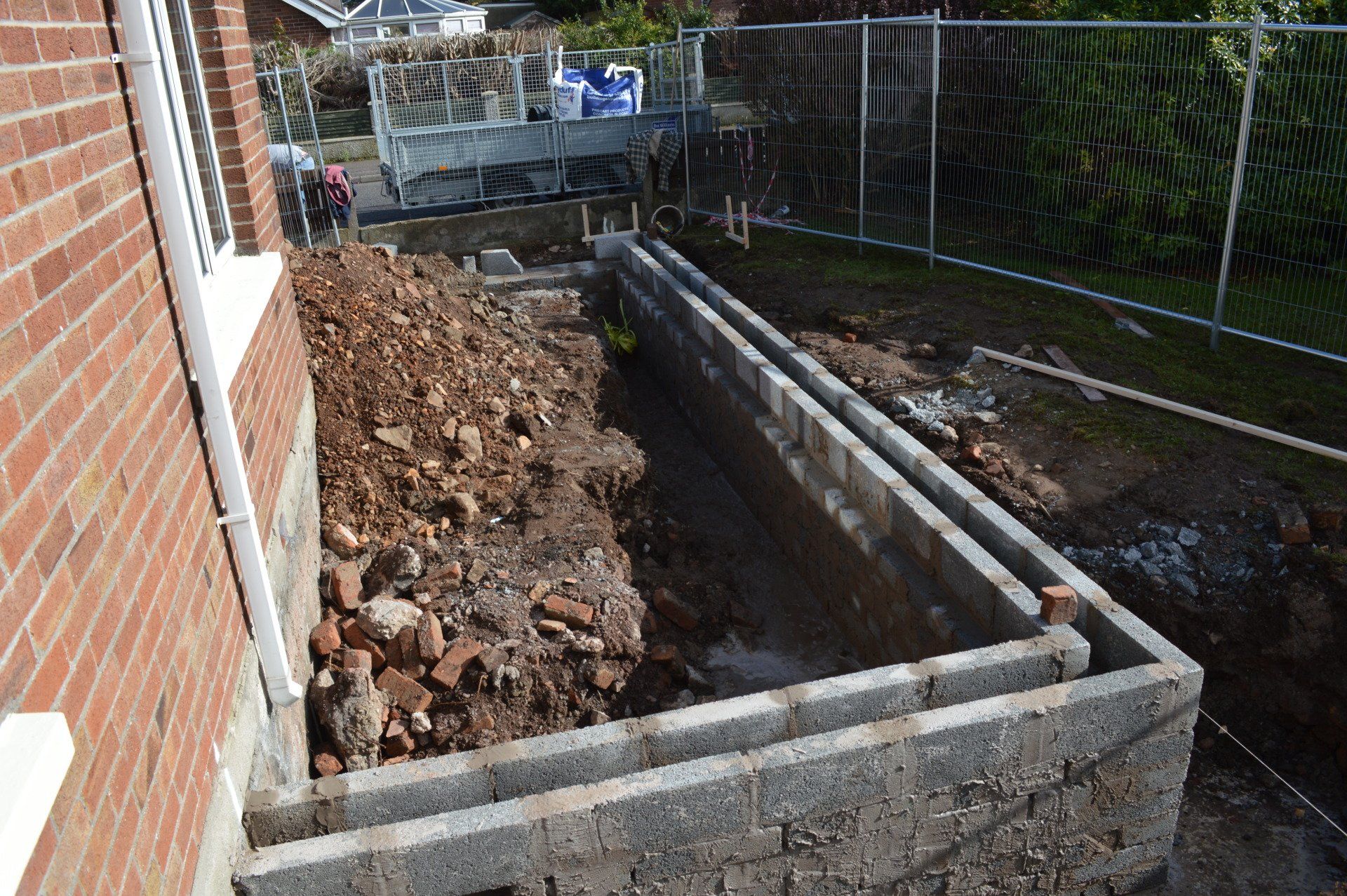 A large brick wall is being built in front of a brick building.