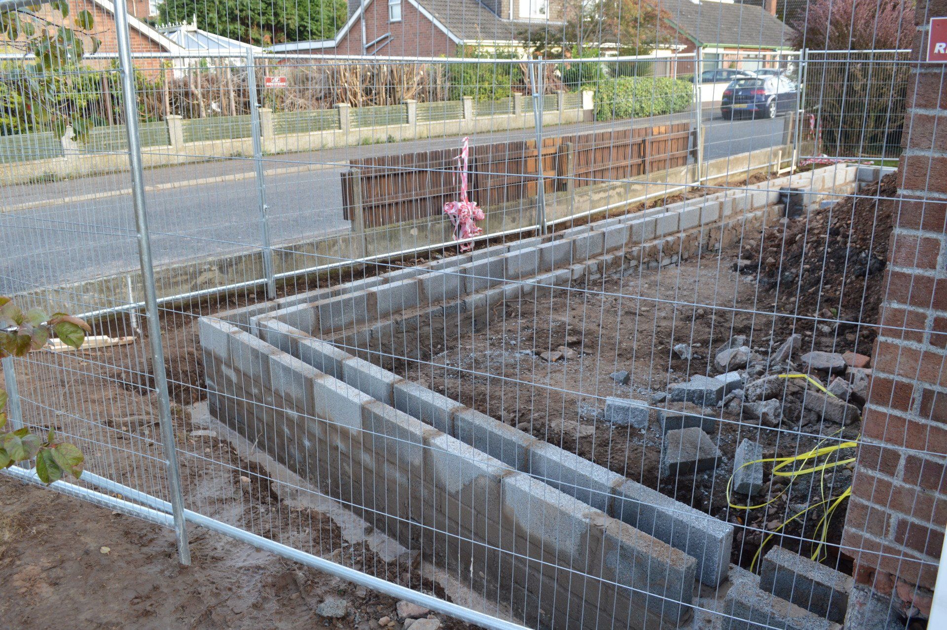 A brick wall is being built behind a wire fence