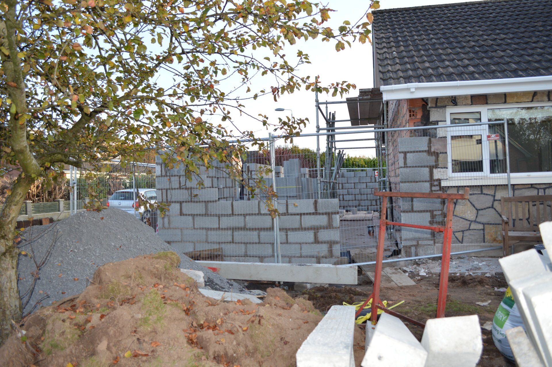A brick wall is being built in front of a house