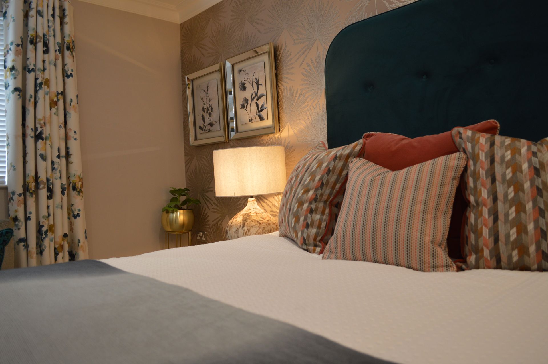 A bedroom with a bed , lamp , and pictures on the wall.