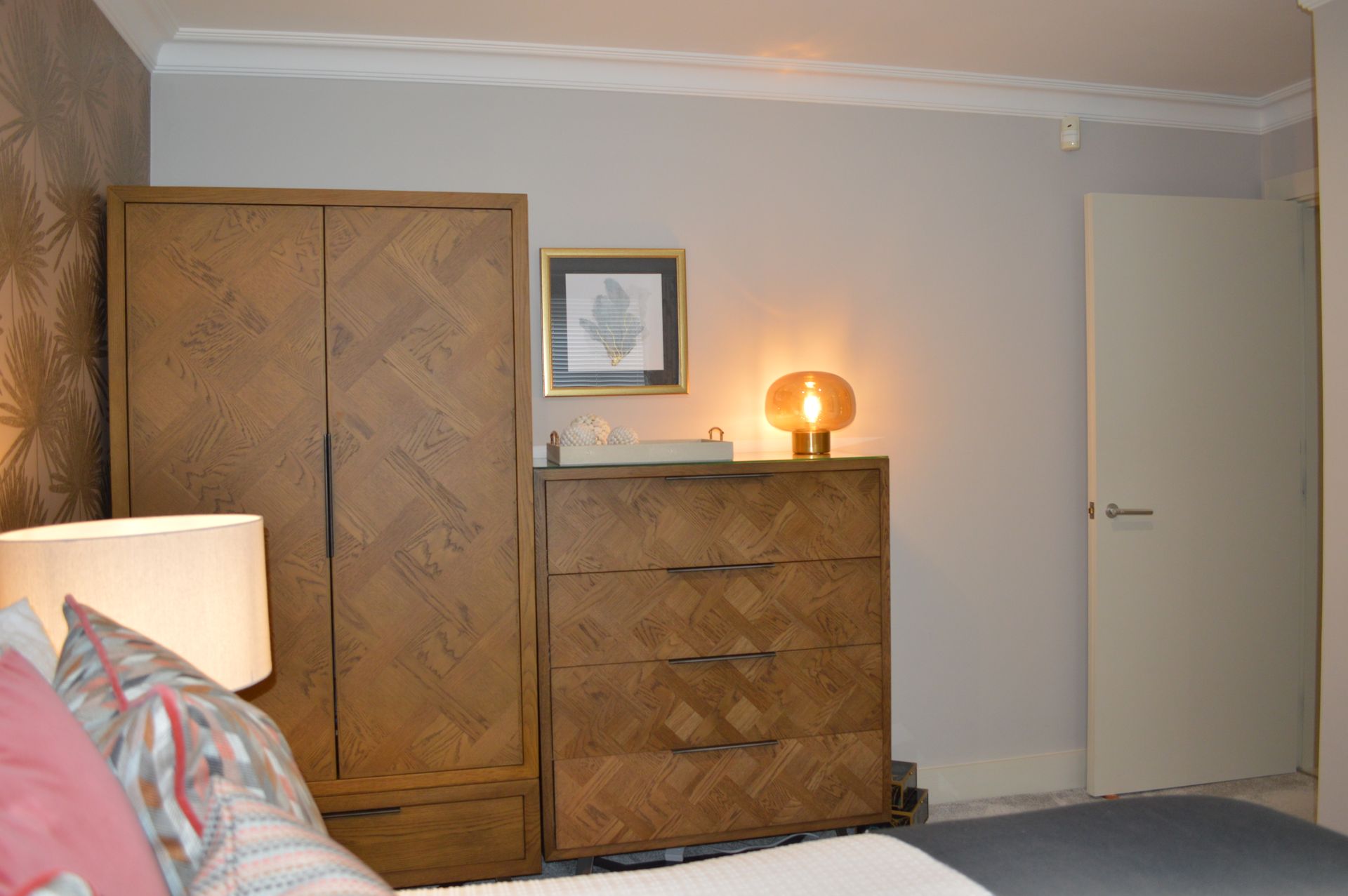 A bedroom with a bed , dresser , and wardrobe.