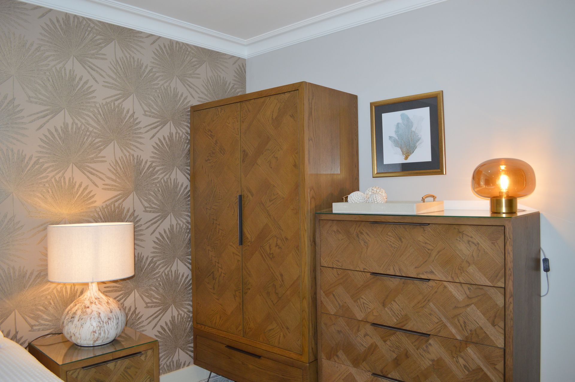 A bedroom with a dresser , nightstand , lamp and wardrobe.