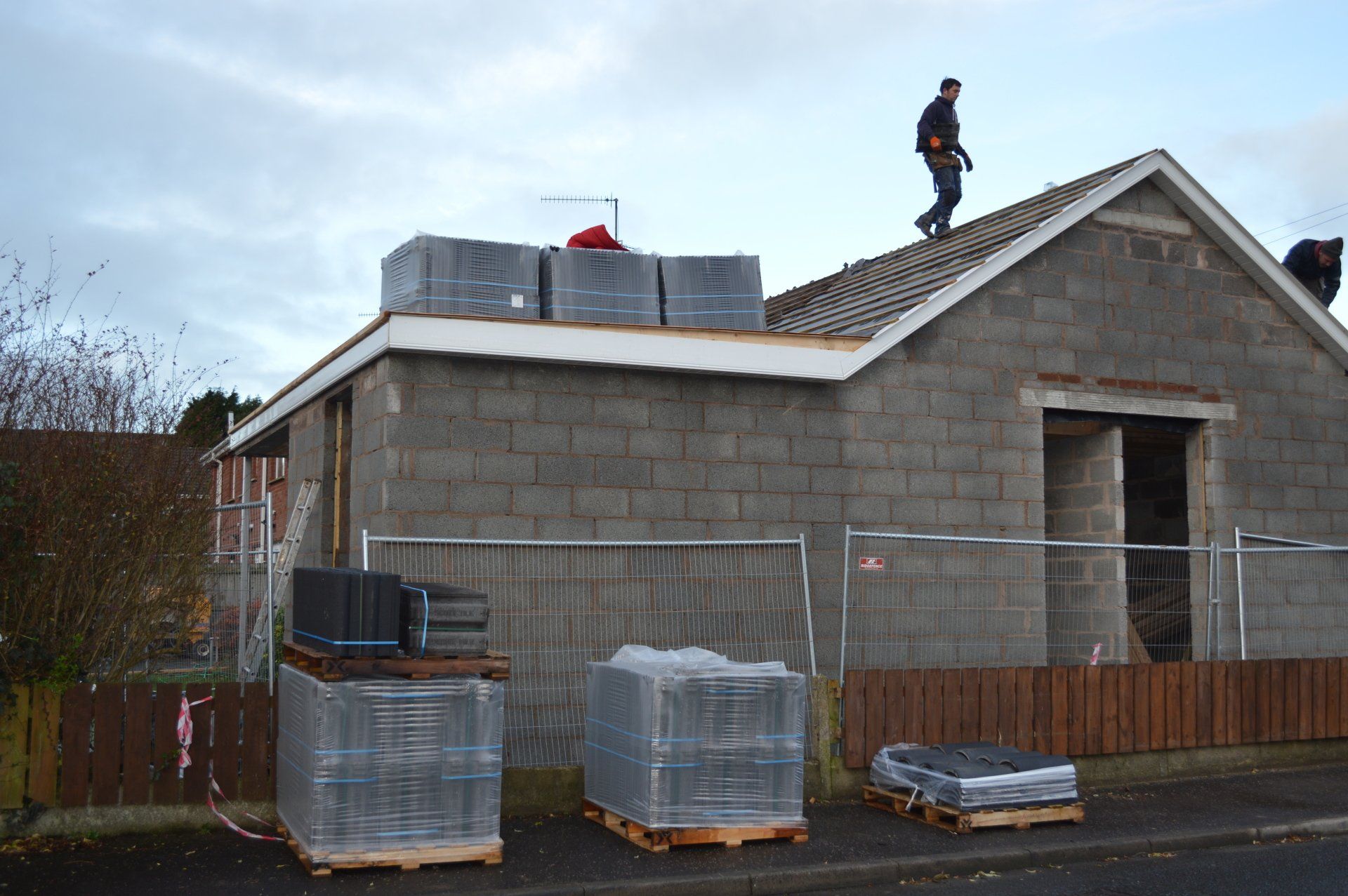 Two men are working on the roof of a brick building