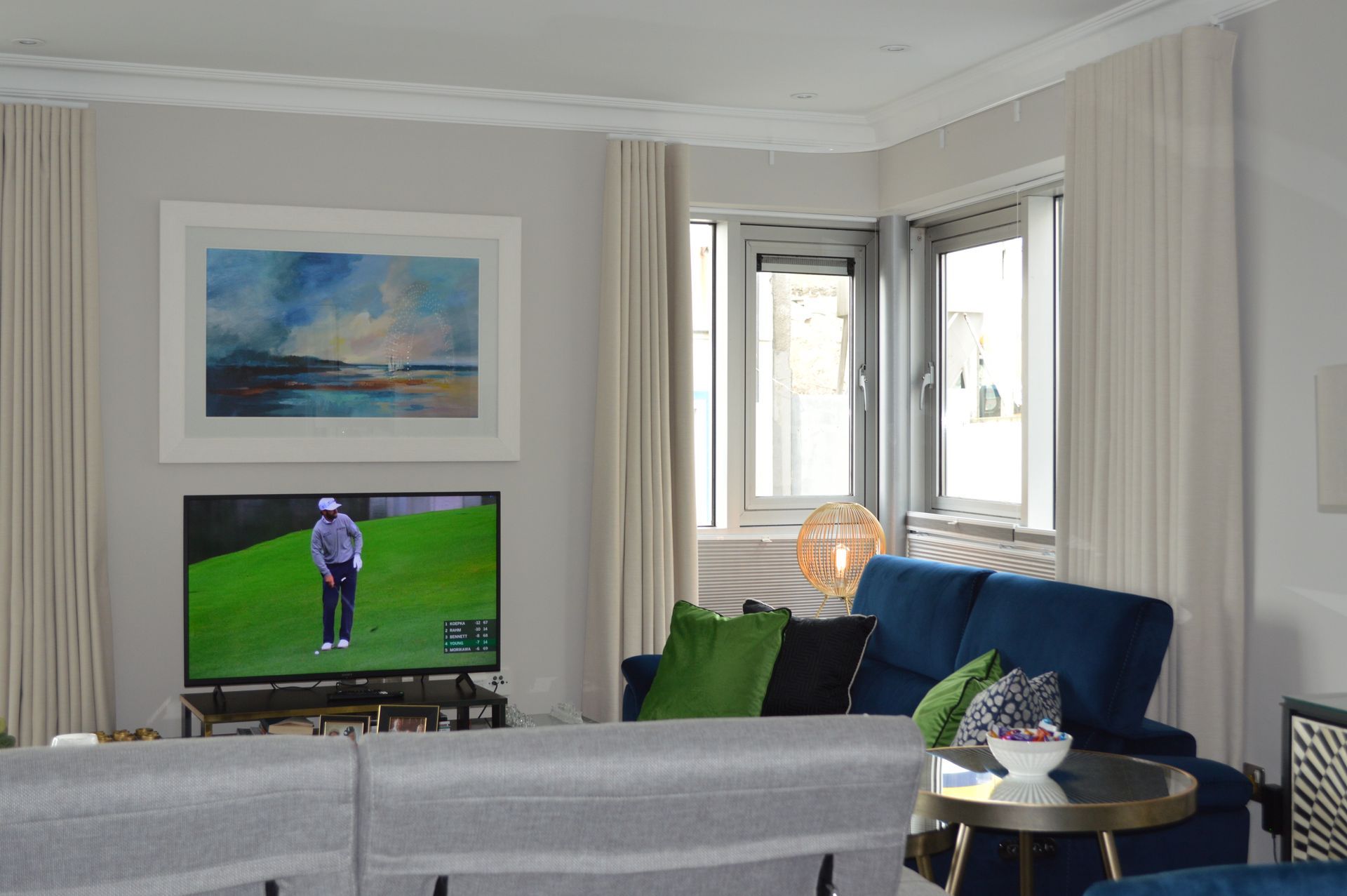 A living room with a couch , table , television and a painting on the wall.