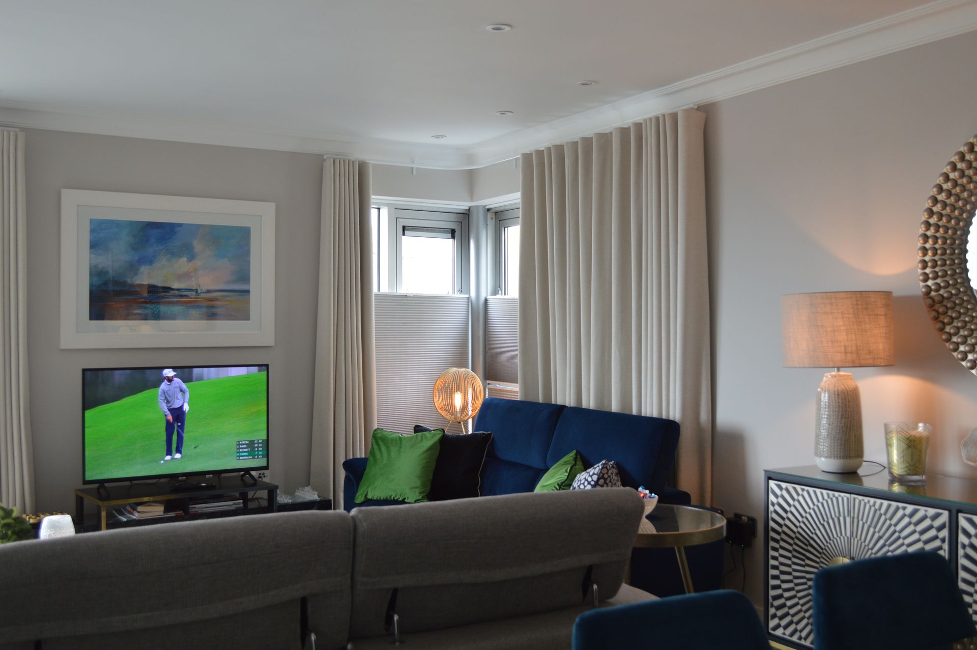 A living room with a couch , chairs , a television and a mirror.