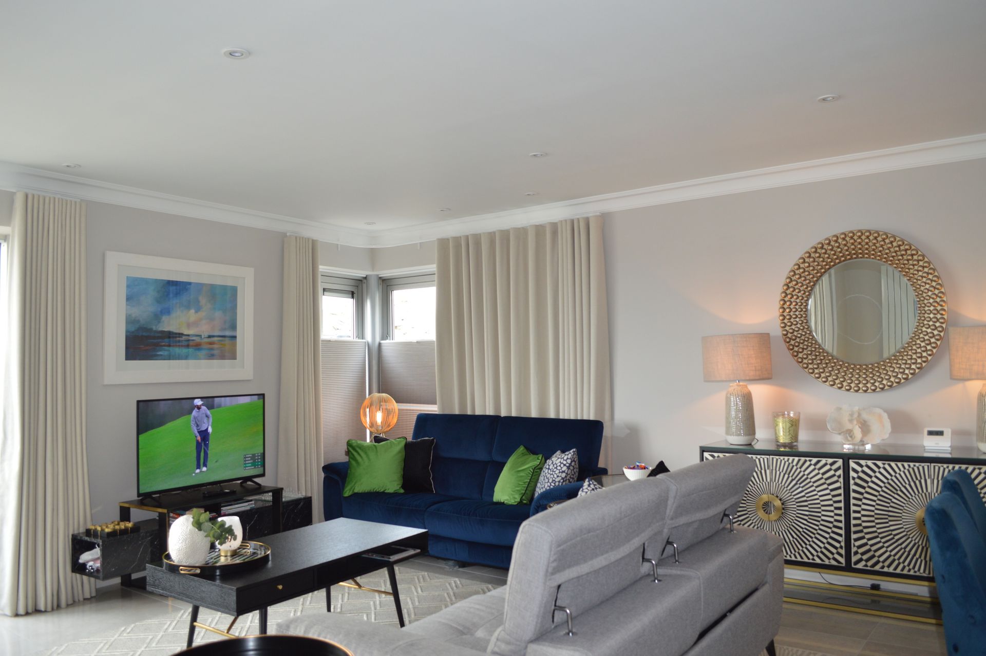 A living room with a couch , table , television and mirror.